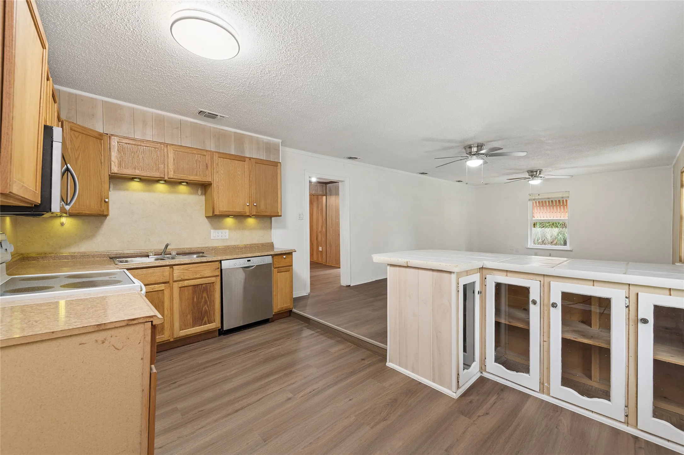 Light wood-finish cabinetry, stainless steel dishwasher, wood-finish flooring, recessed lighting, and ceiling fans