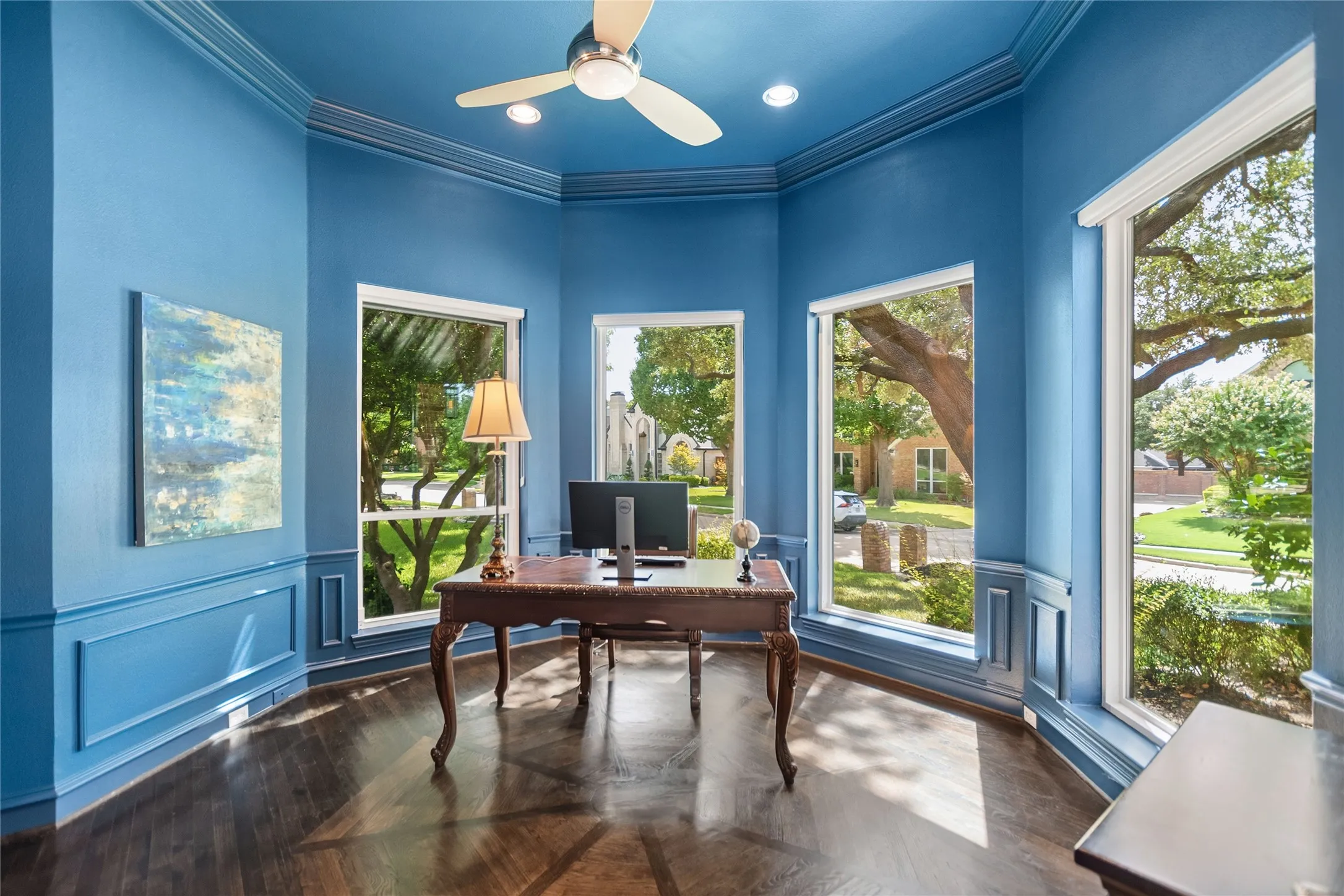 Corner room featuring dark wood-finish flooring, floor-to-ceiling windows, extensive crown molding, recessed lighting, and a ceiling fan