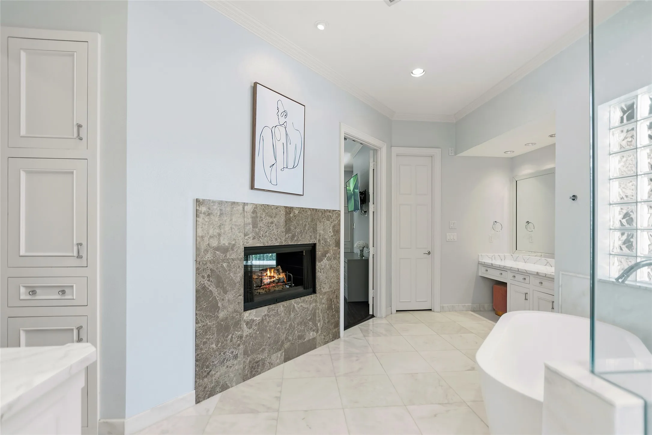 Tiled flooring complementing an integrated fireplace, freestanding tub, and glass block shower enclosure