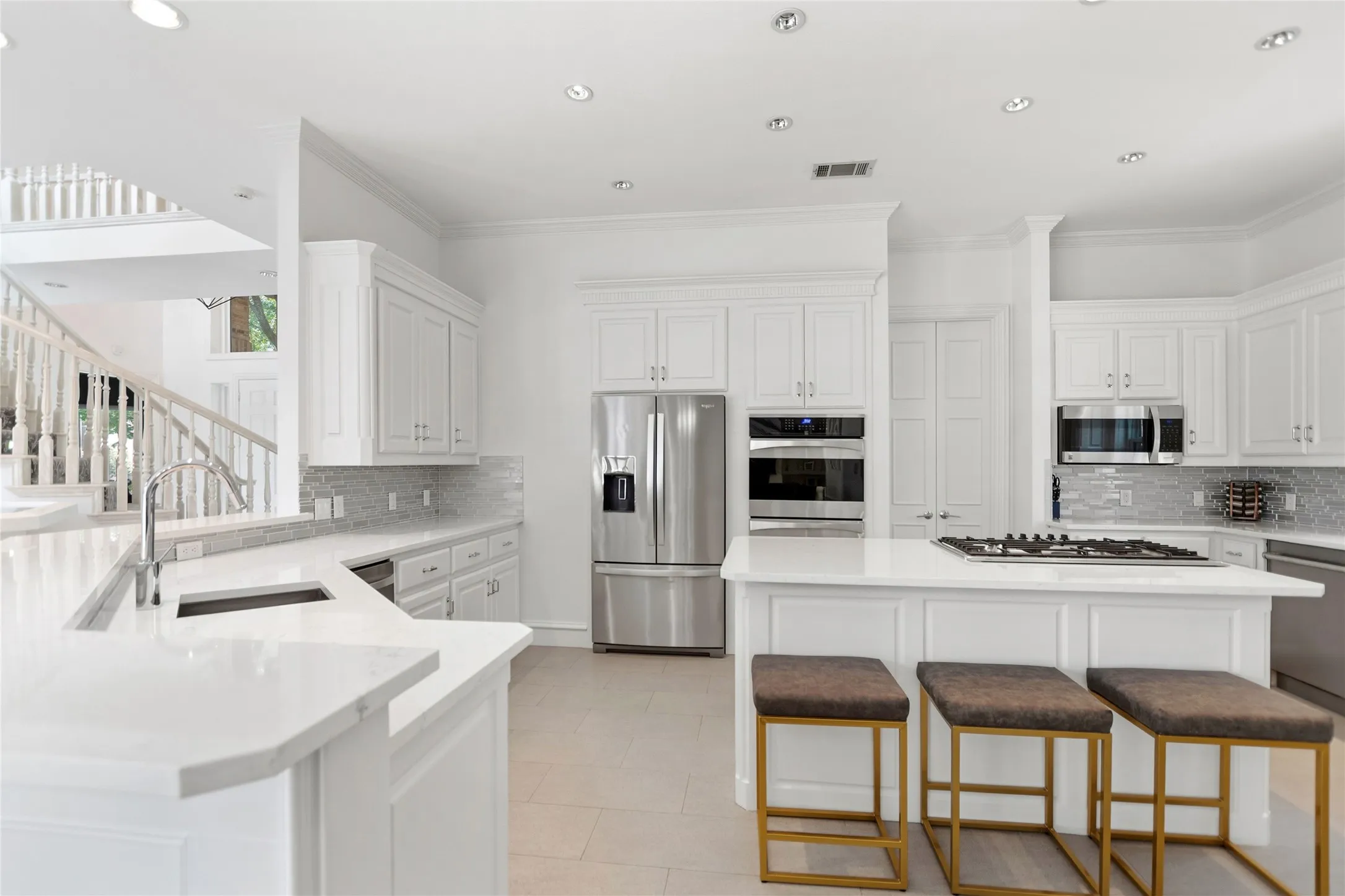 Bright kitchen featuring white cabinetry, light countertops, and stainless steel appliances