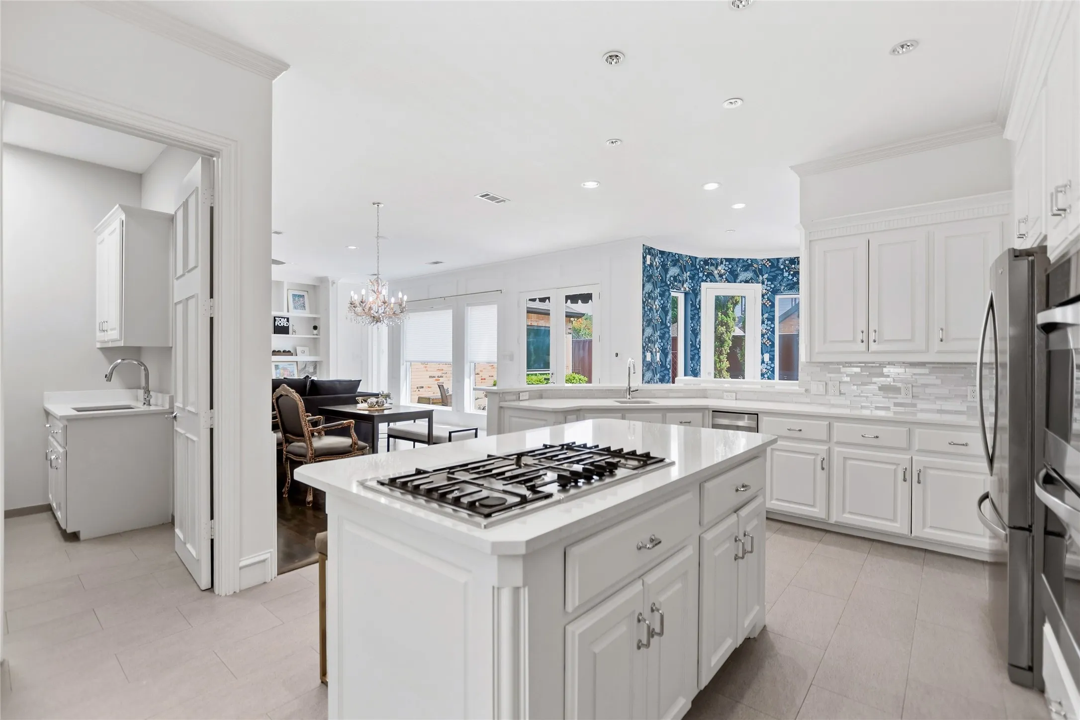 Kitchen featuring a central island with a gas cooktop, white cabinetry, integrated stainless steel appliances, and wood-finish flooring