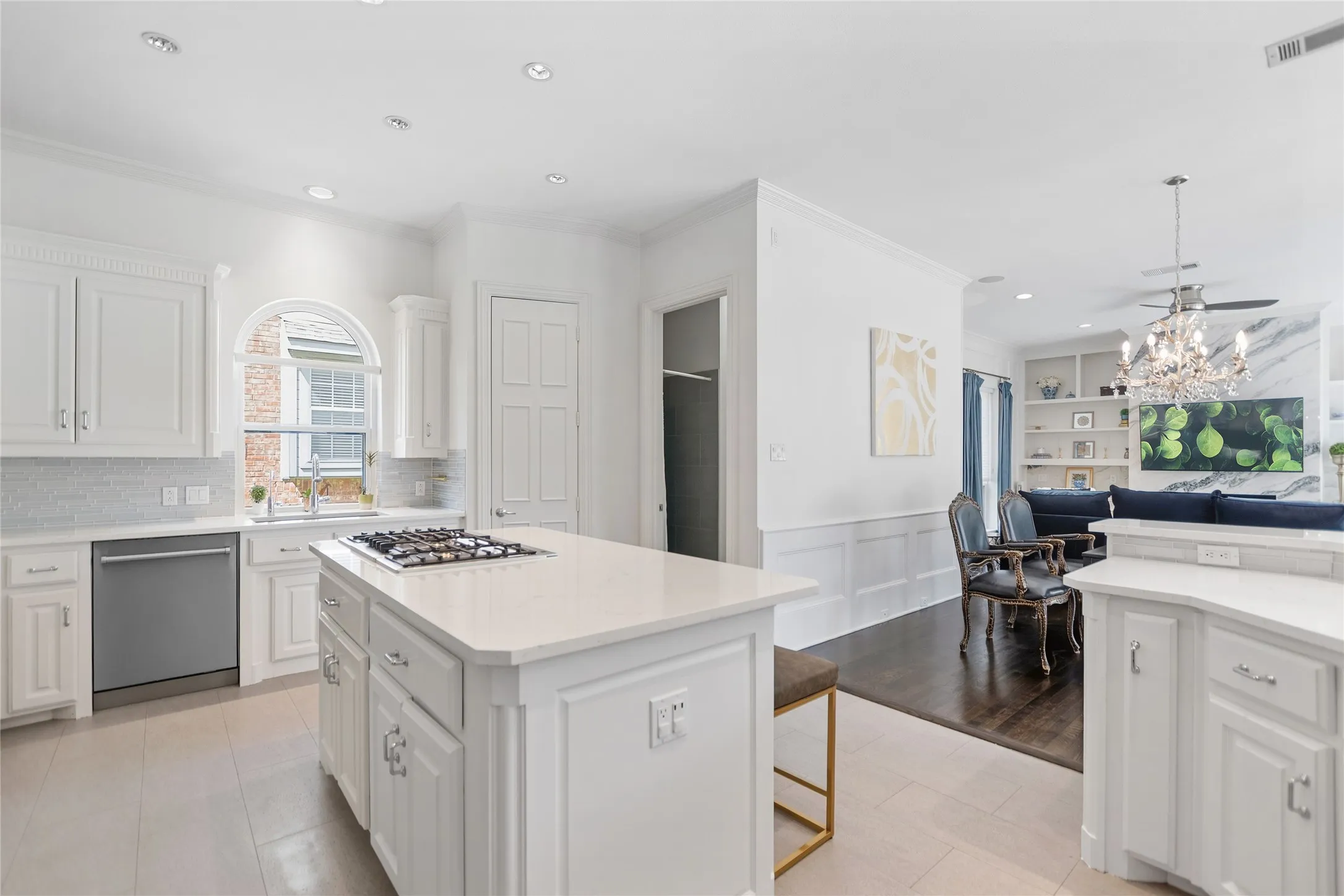 White kitchen featuring an island with a gas cooktop, recessed lighting, and an arched window