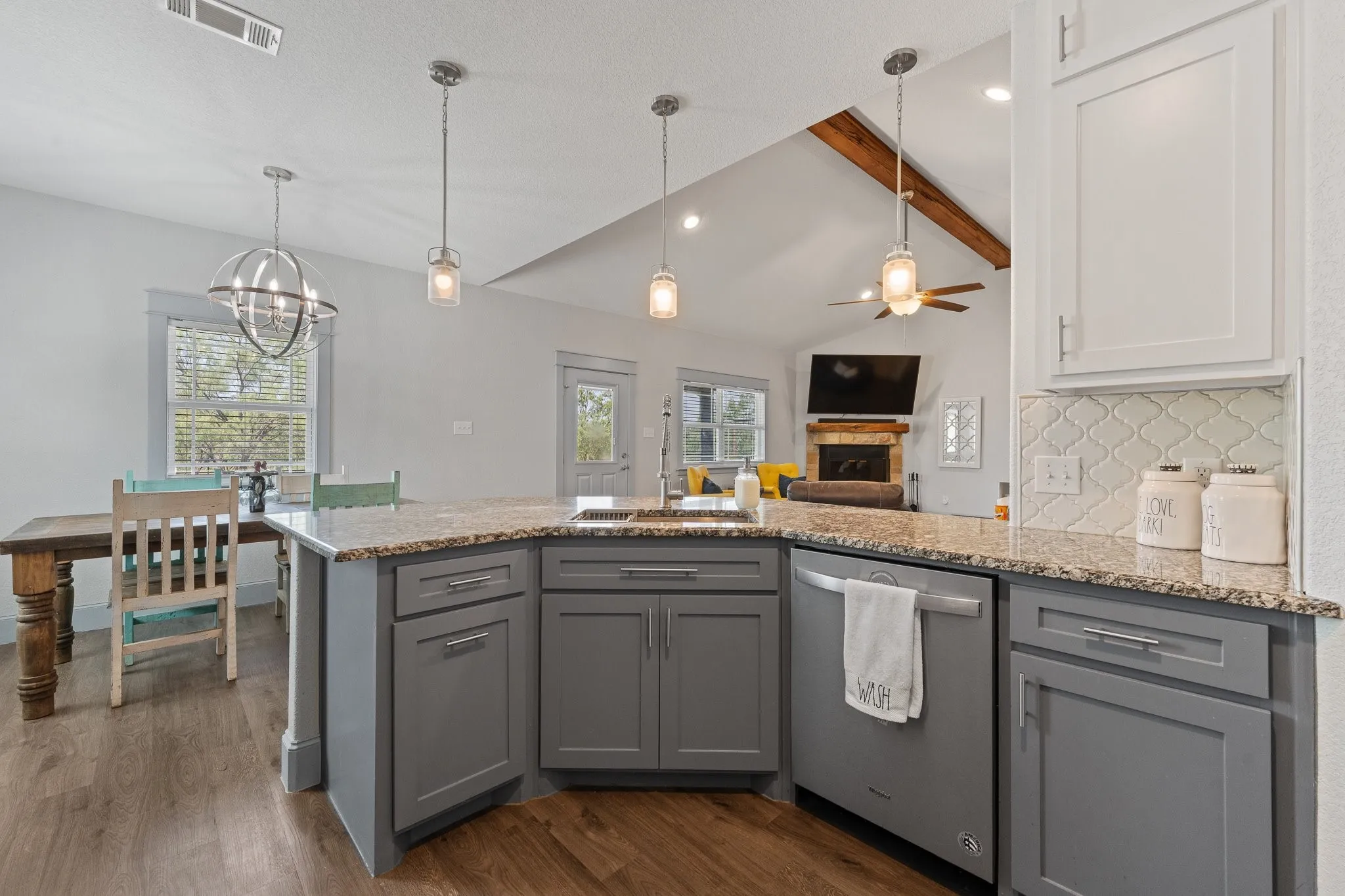 Chef's kitchen showcases gray cabinetry with granite countertops, stainless steel appliances, and a large center island with seating