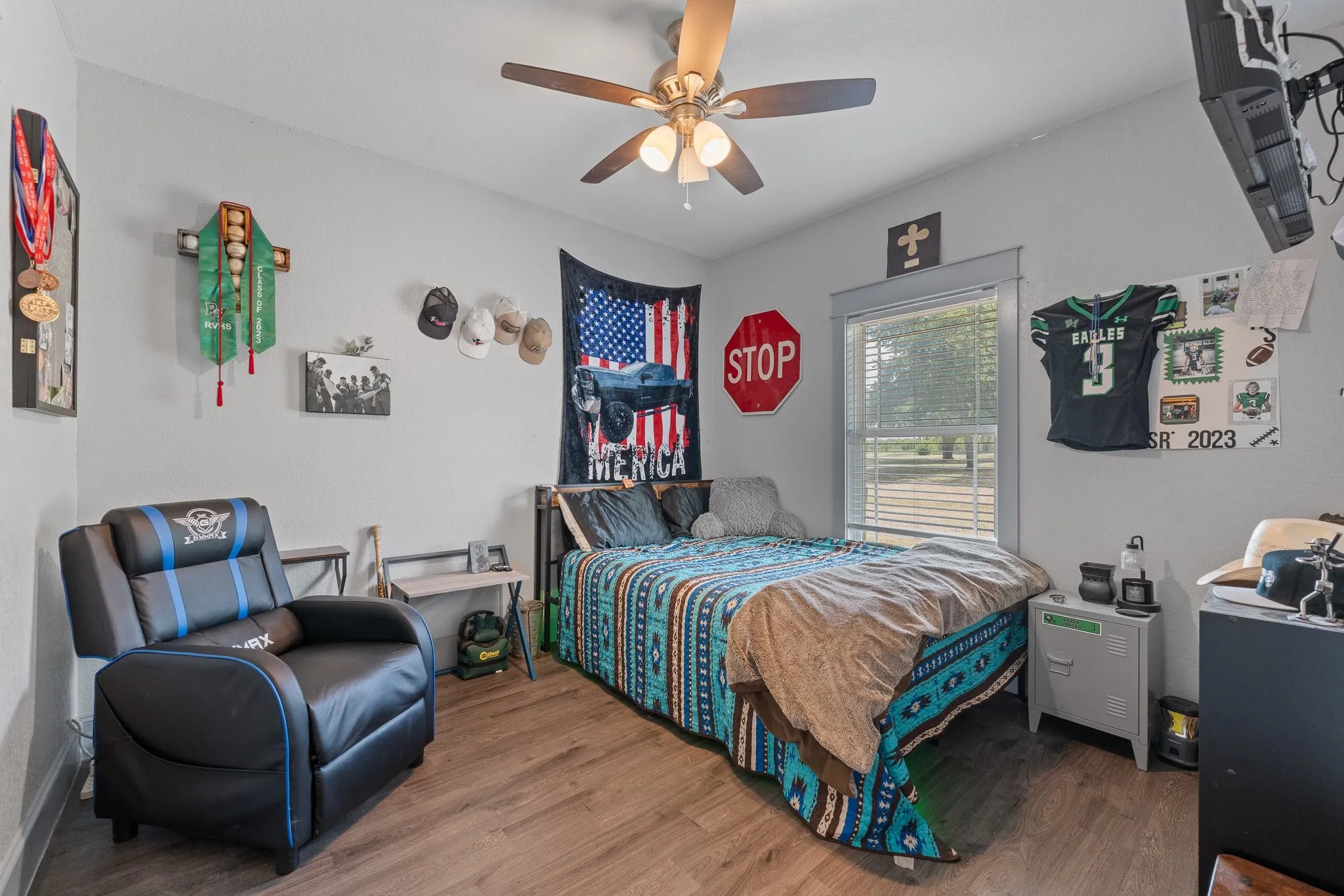 2nd Bright interior bedroom featuring wood-finish flooring, a ceiling fan with integrated lighting, and a window with blinds