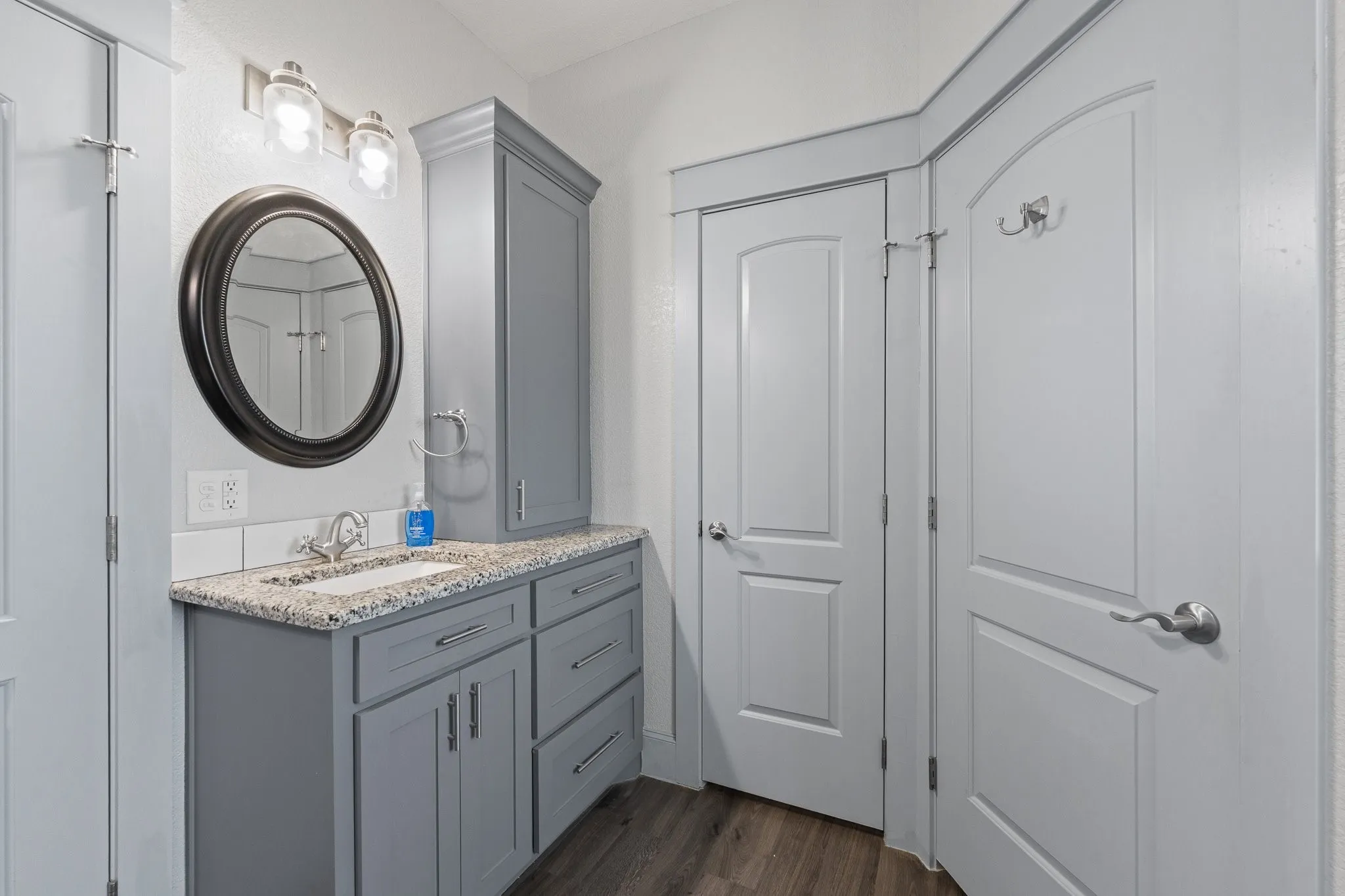 Bathroom vanity featuring gray cabinetry with brushed nickel hardware, a speckled countertop, and a white rectangular undermount sink