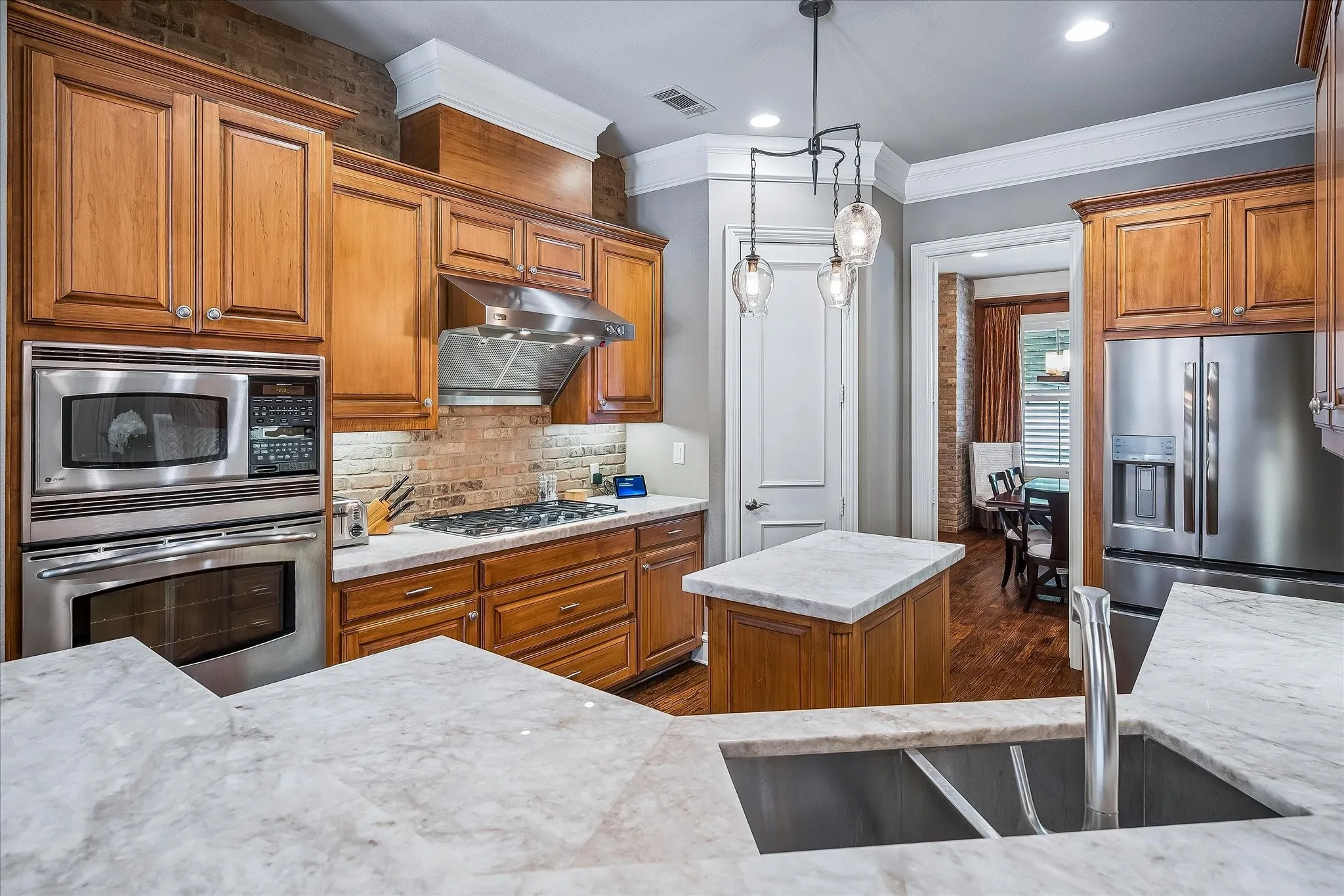 Custom quartz countertops, under mount lighting gives dramatic feel to the kitchen, bricked accent wall on one wall. Walk in pantry.