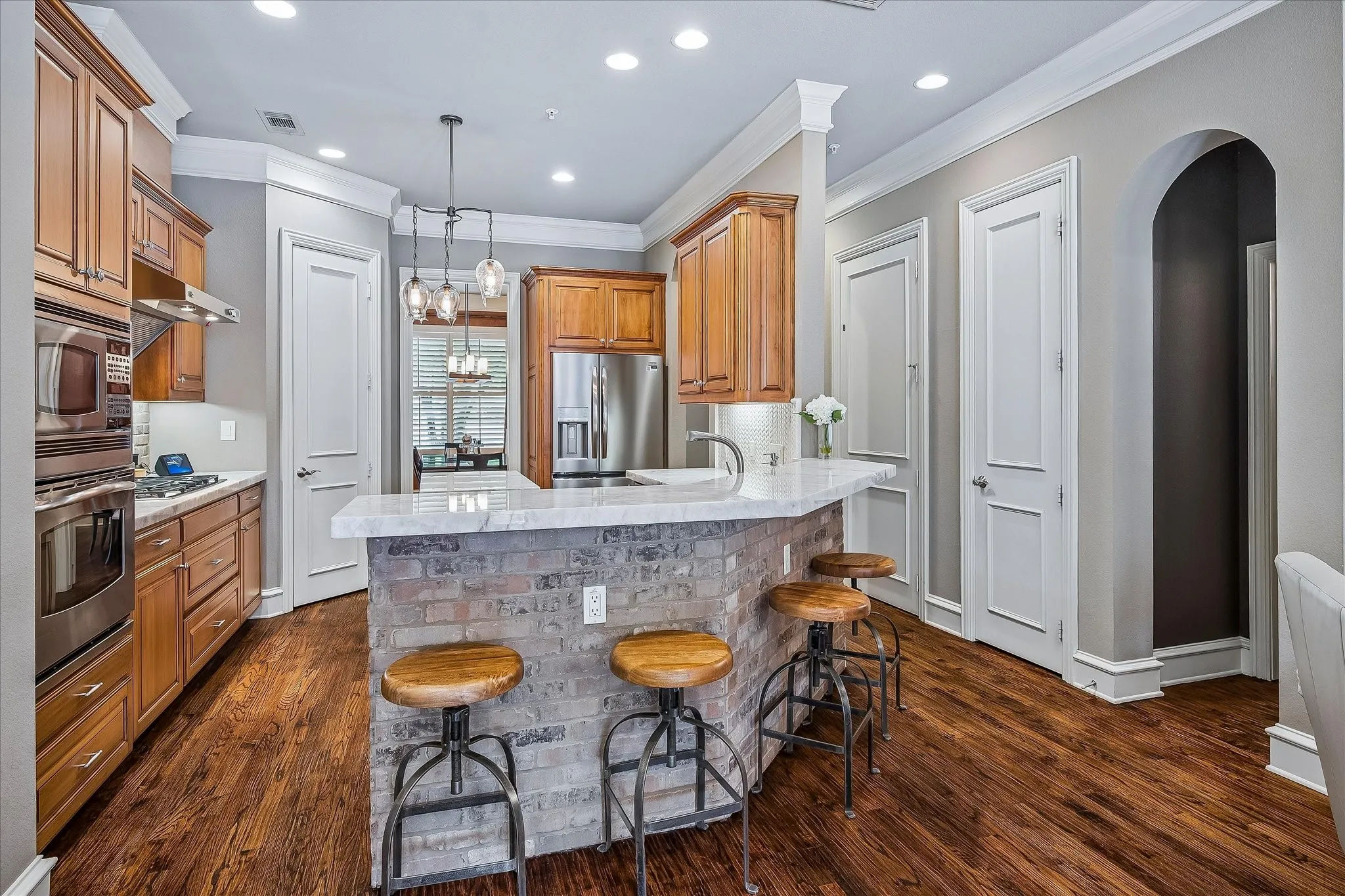 Breakfast bar is counter height, bricked accent under counter bar. Arched doorway opens to half bath, closet, elevator door at hallway.