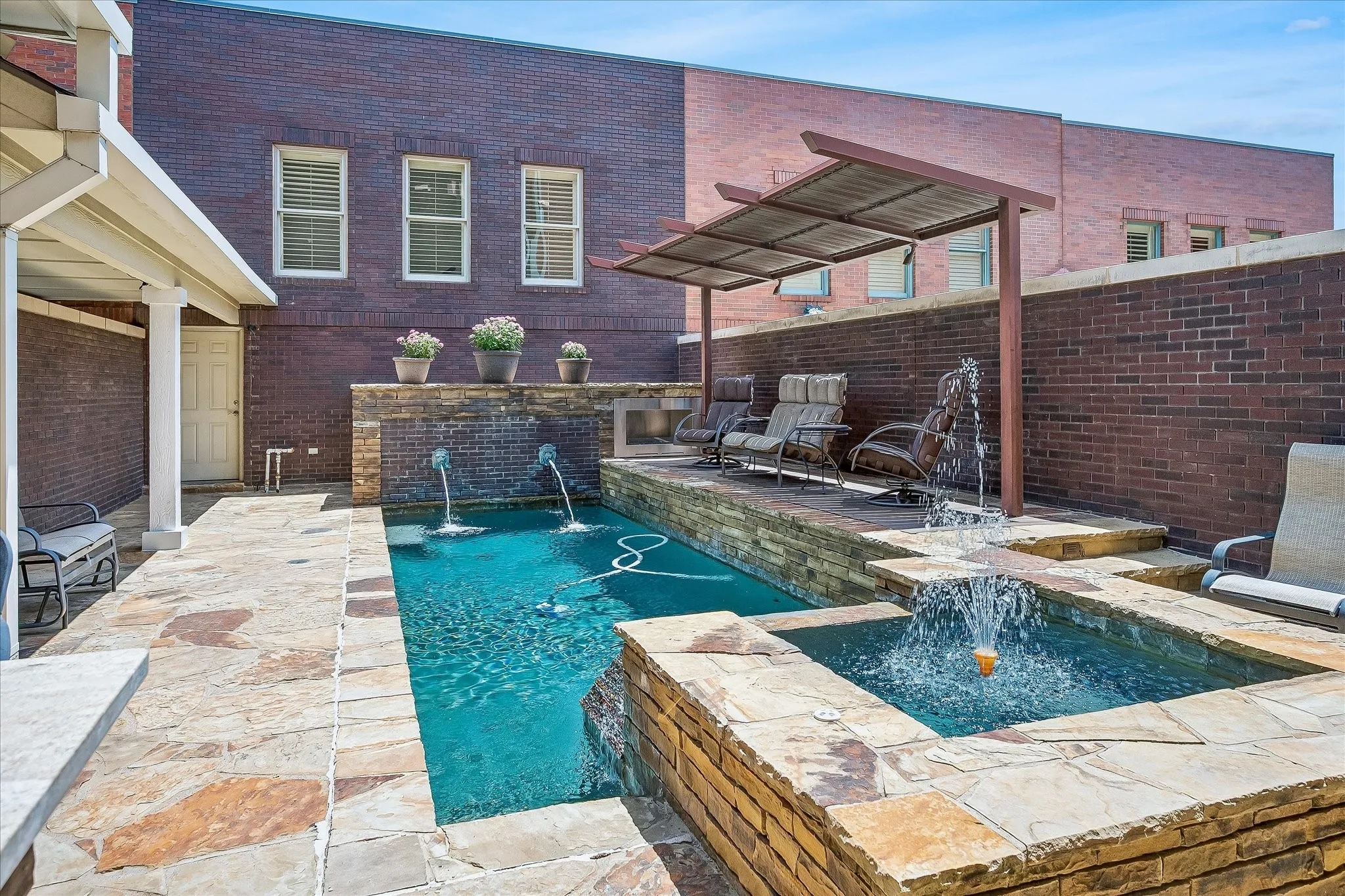 Raised sitting area with covered arbor to sit and enjoy your own pool and courtyard. Wall with water features add character to the landscape.