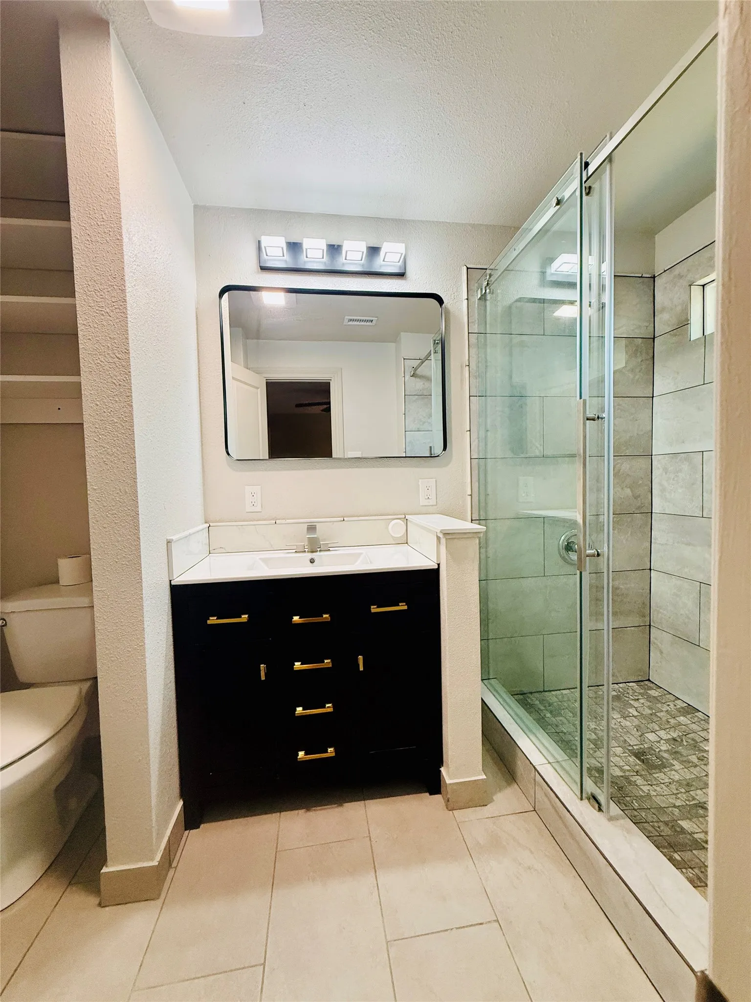 Modern bathroom featuring a glass-enclosed shower with tiled walls and a mosaic floor