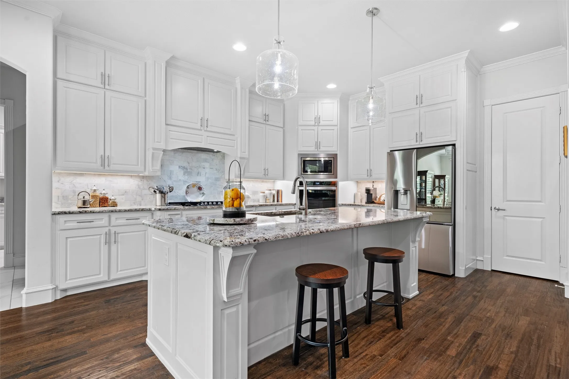 Custom cabinetry from ceiling to the floor, double ovens, gorgeous granite counters, under cabinet lighting and outlets, and the entrance to the incredibly spacious walk in pantry.