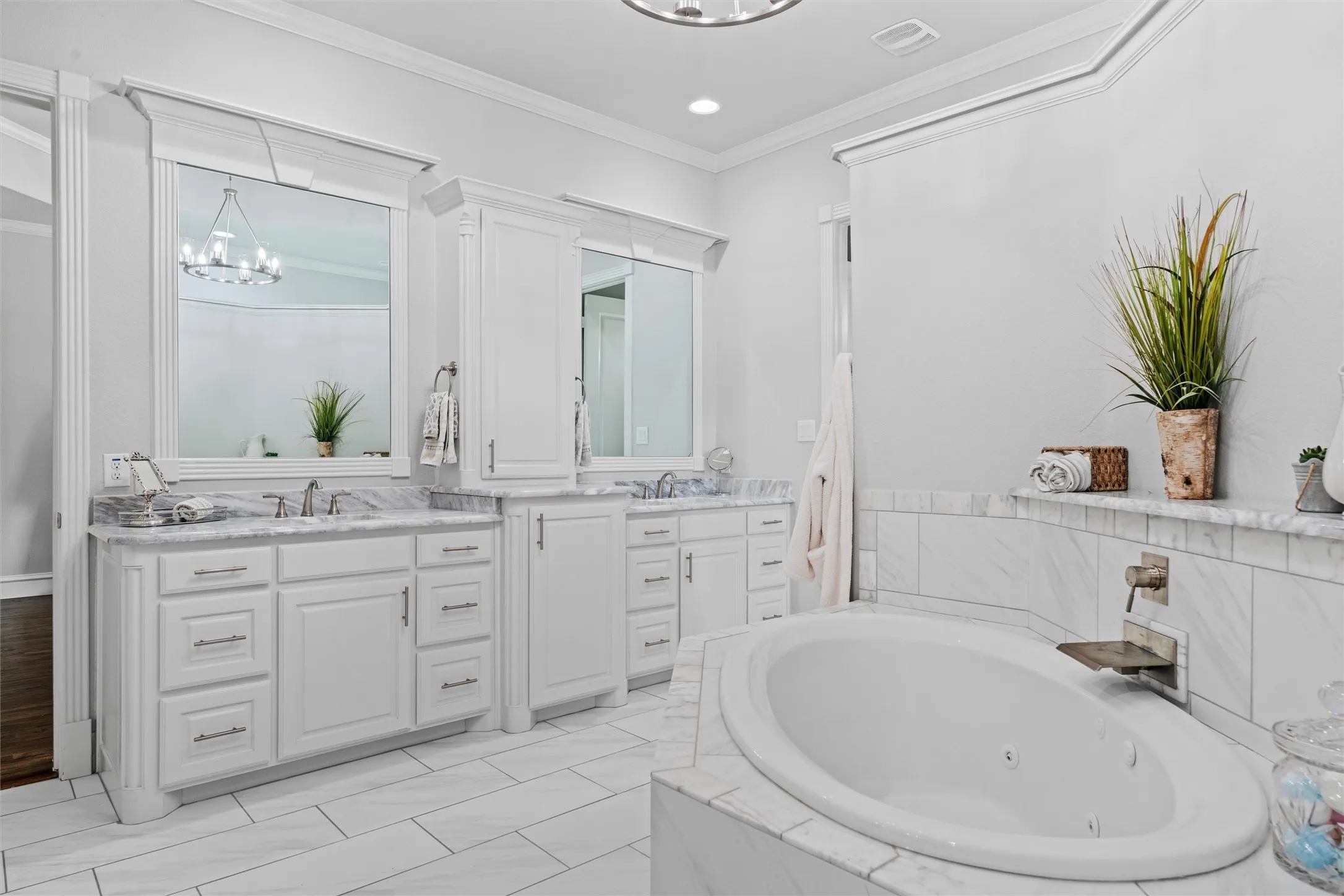 One side of the primary bath with two separate vanity areas, two sinks, and an abundance of cabinets and drawers.