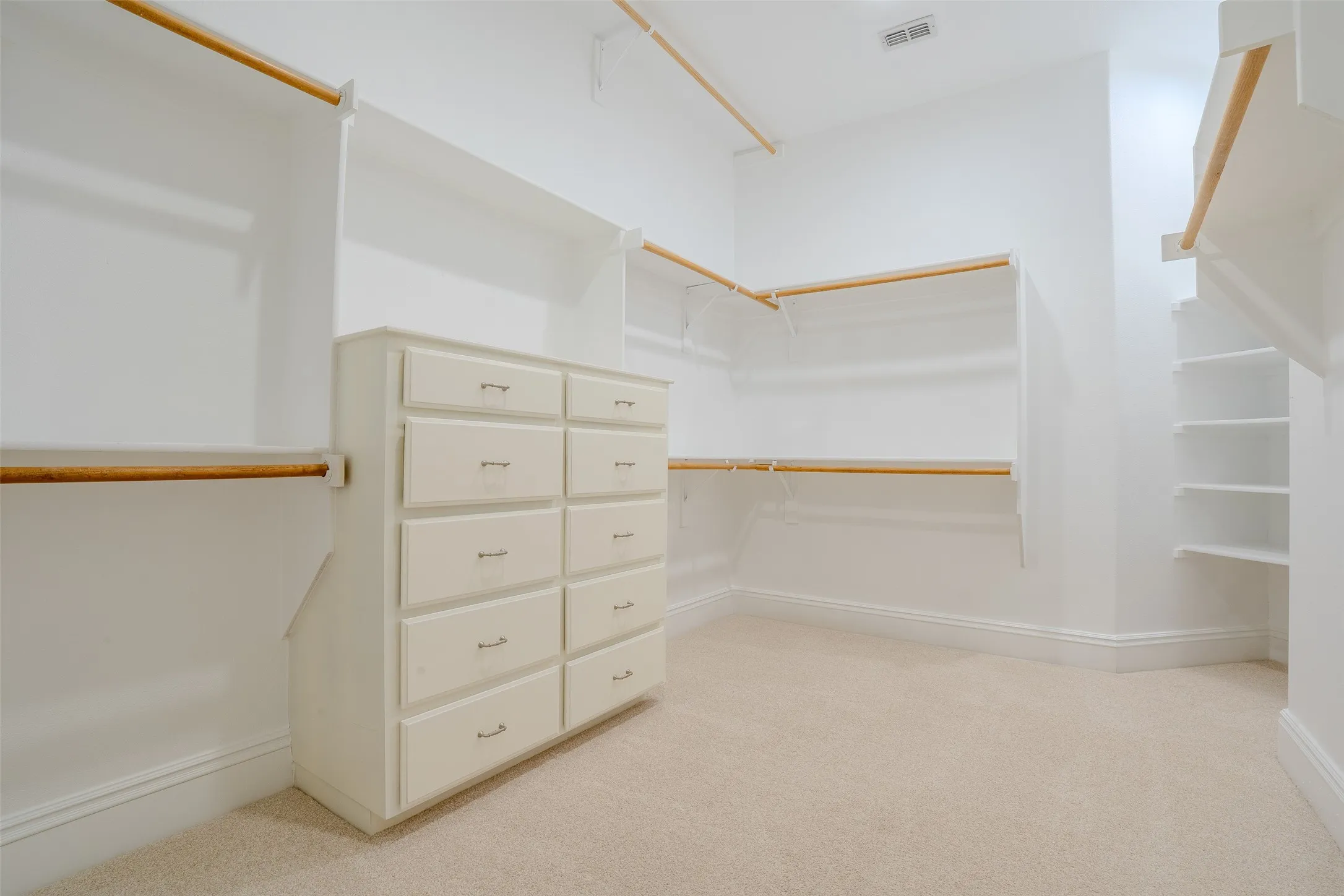 large primary closet with plenty of shelving and built in dresser