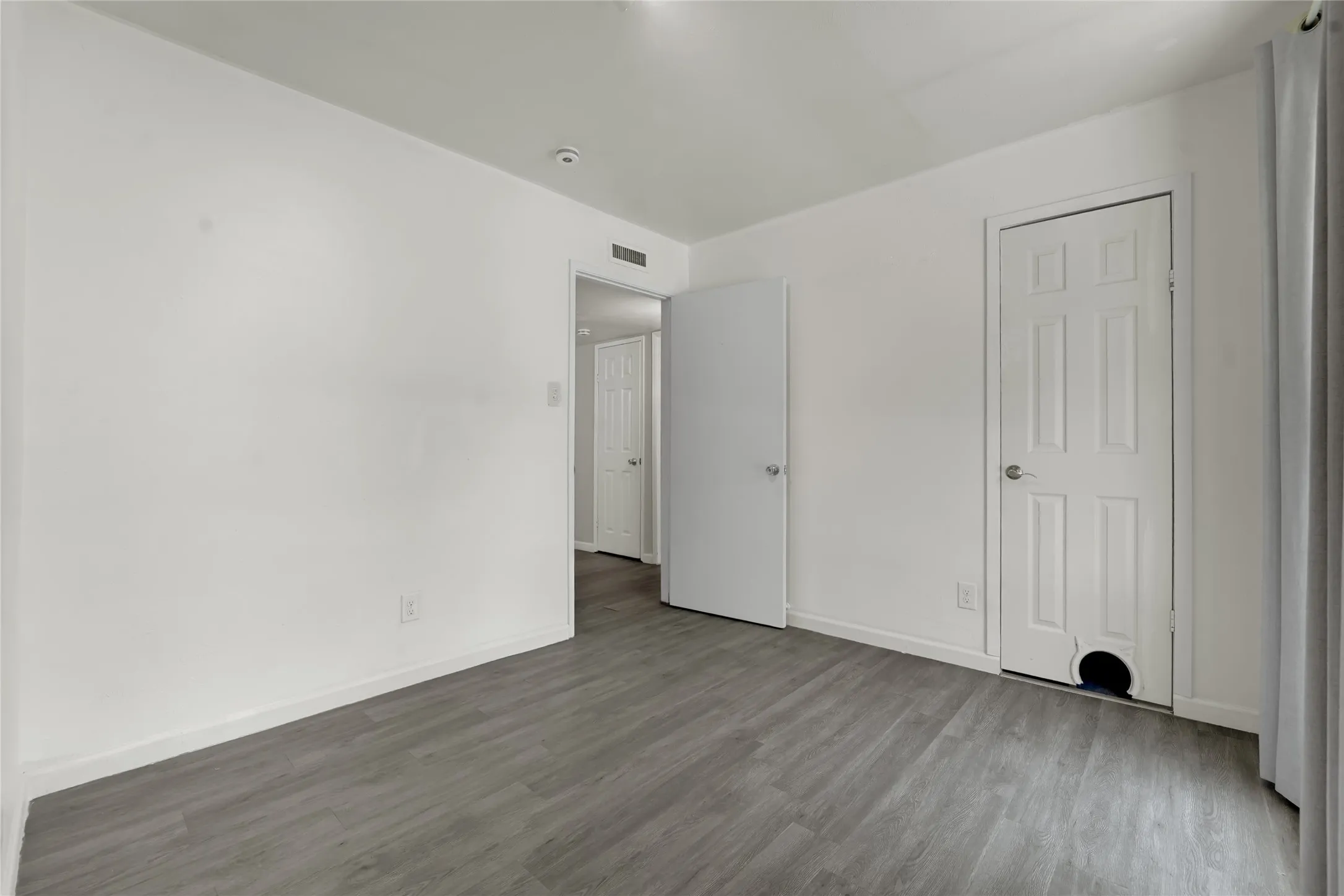 Room featuring wood-finish flooring, white walls, and white baseboards