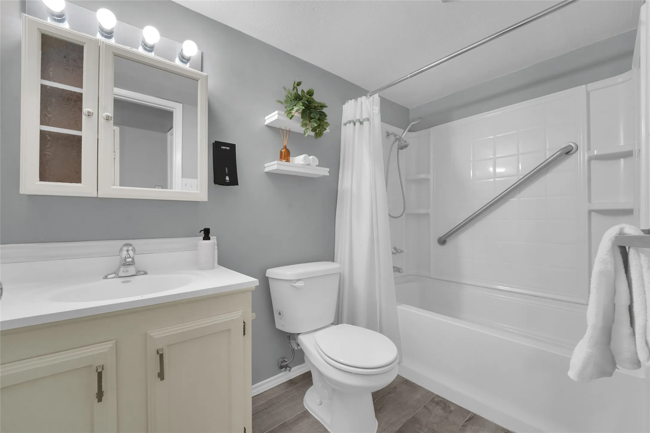 Bathroom featuring a white vanity with integrated sink, chrome faucet, and mirrored medicine cabinet with integrated lighting
