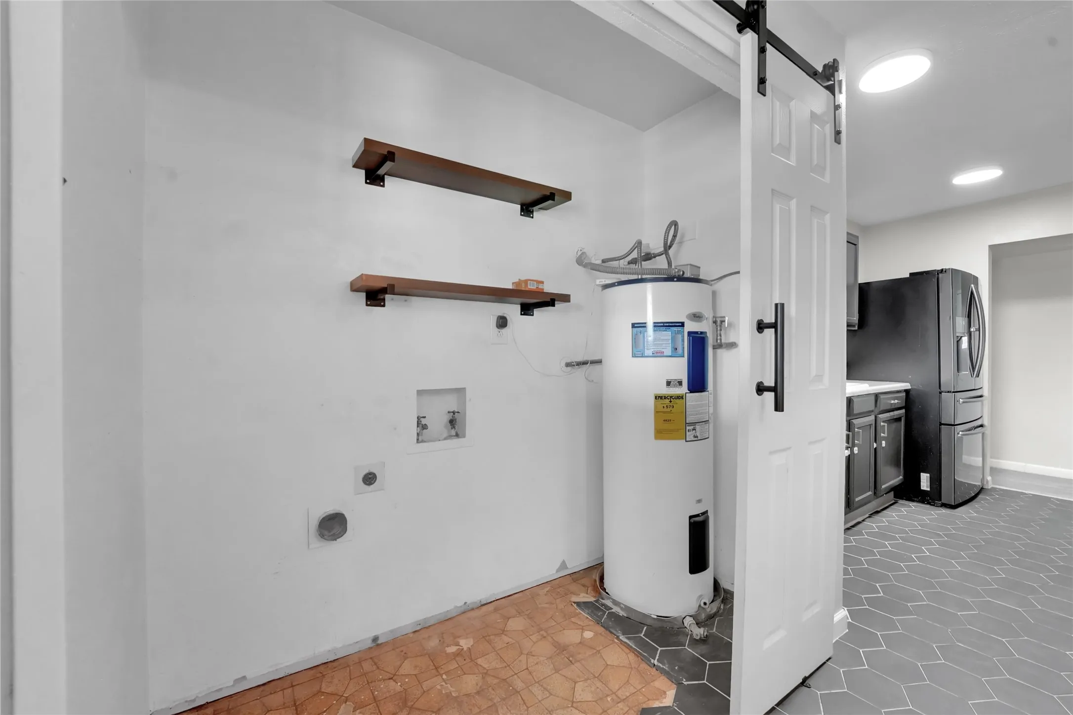 Laundry area featuring a water heater, two wall-mounted shelves, and a barn door entry