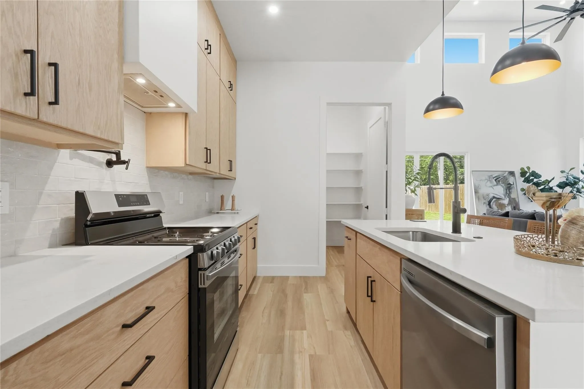 Contemporary kitchen featuring light wood-finish cabinetry, white countertops, and stainless steel appliances