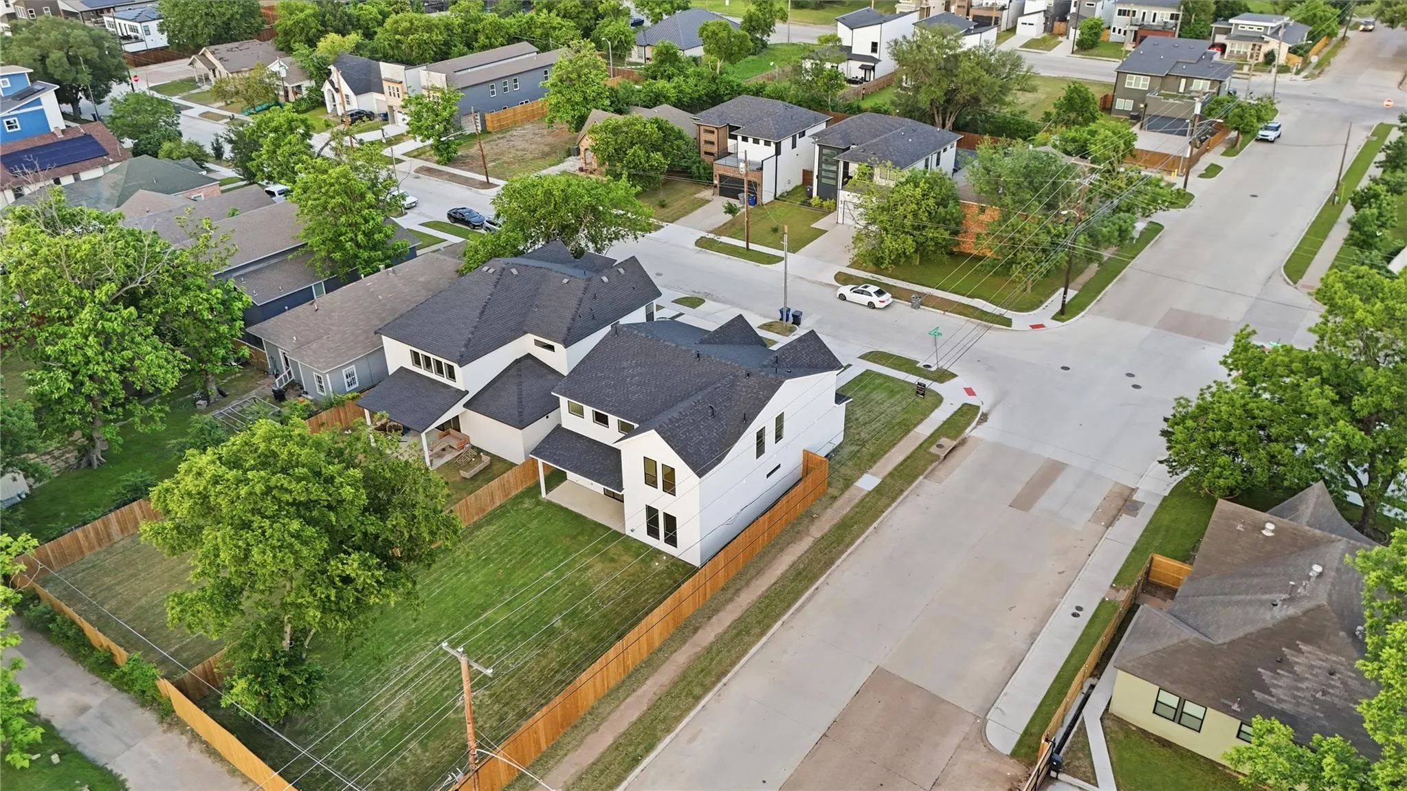 Aerial perspective showcasing a modern white residence with a dark roof