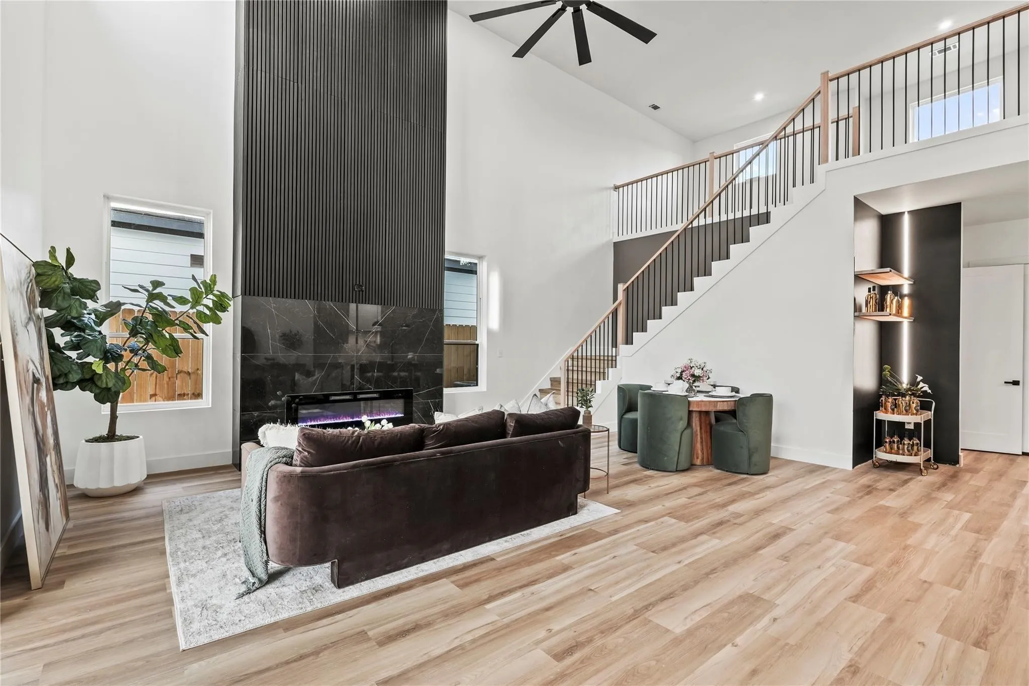 Two-story living area featuring a prominent fireplace with a vertical slat wall and a marble-look surround