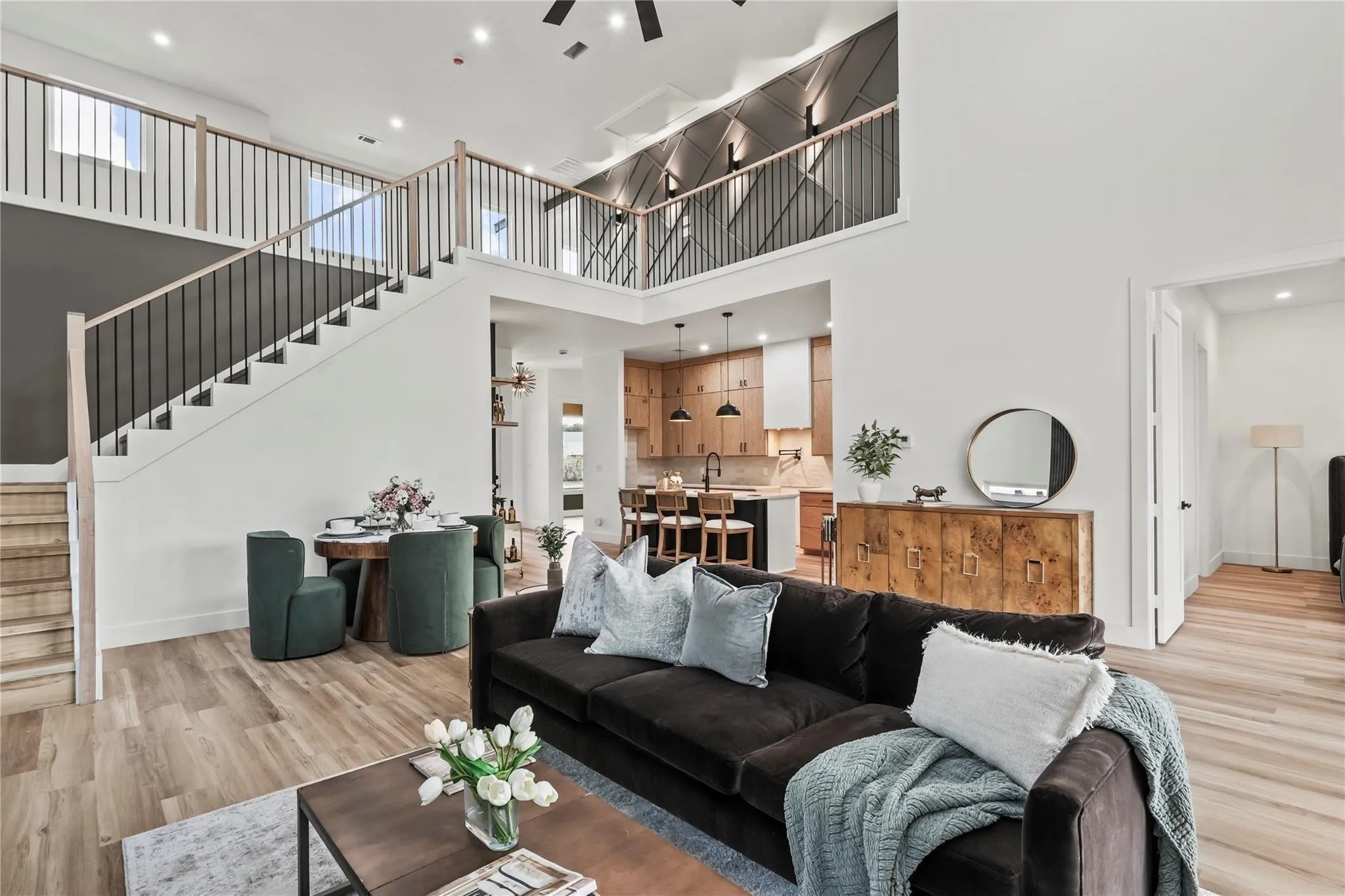 Two-story living area featuring light wood-finish flooring, a contemporary staircase with black metal balusters and light wood handrails, and an open-concept design