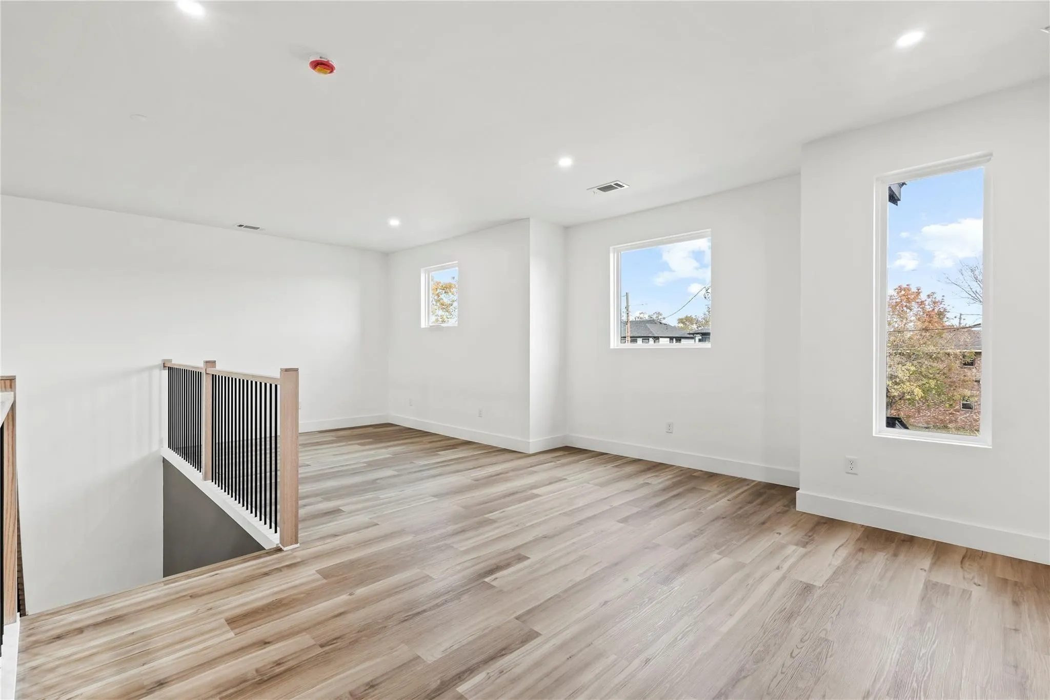 Spacious open area featuring wood-finish flooring, recessed lighting, and multiple windows