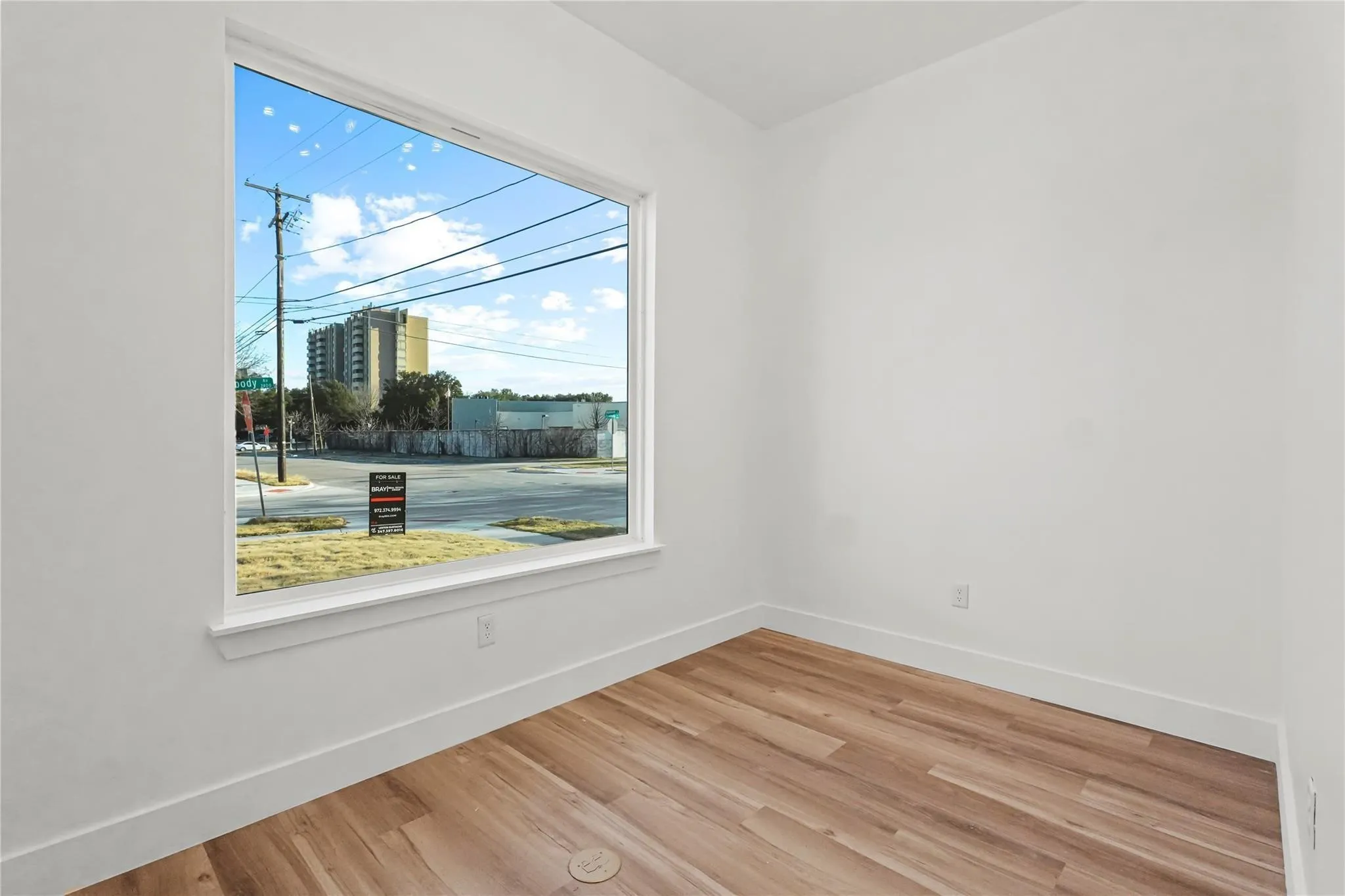Expansive window with white trim, wood-finish flooring, white walls, and white baseboards
