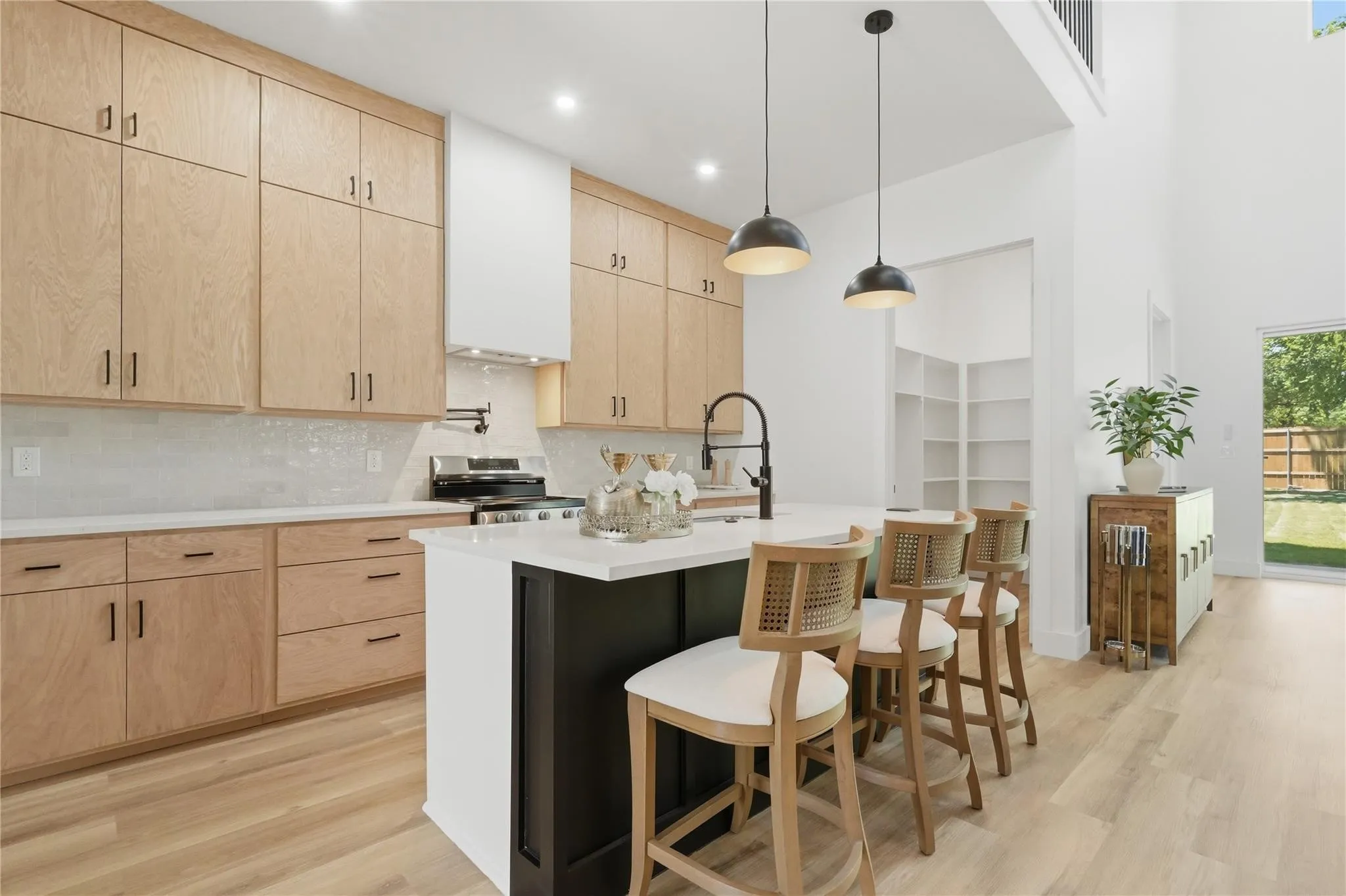 Contemporary kitchen featuring light wood-finish cabinetry, white countertops, and a subway tile backsplash