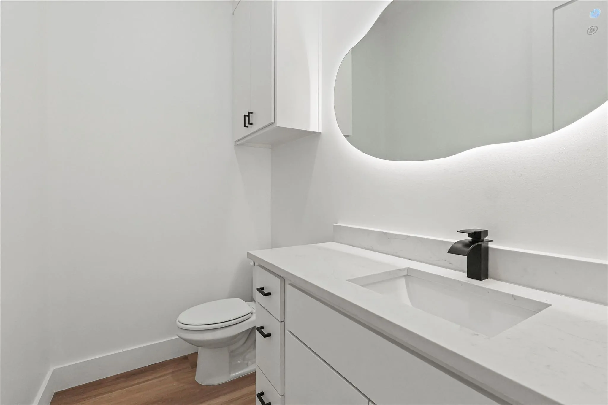 Modern vanity featuring a built-in rectangular sink, light-toned countertop, and matte black waterfall faucet