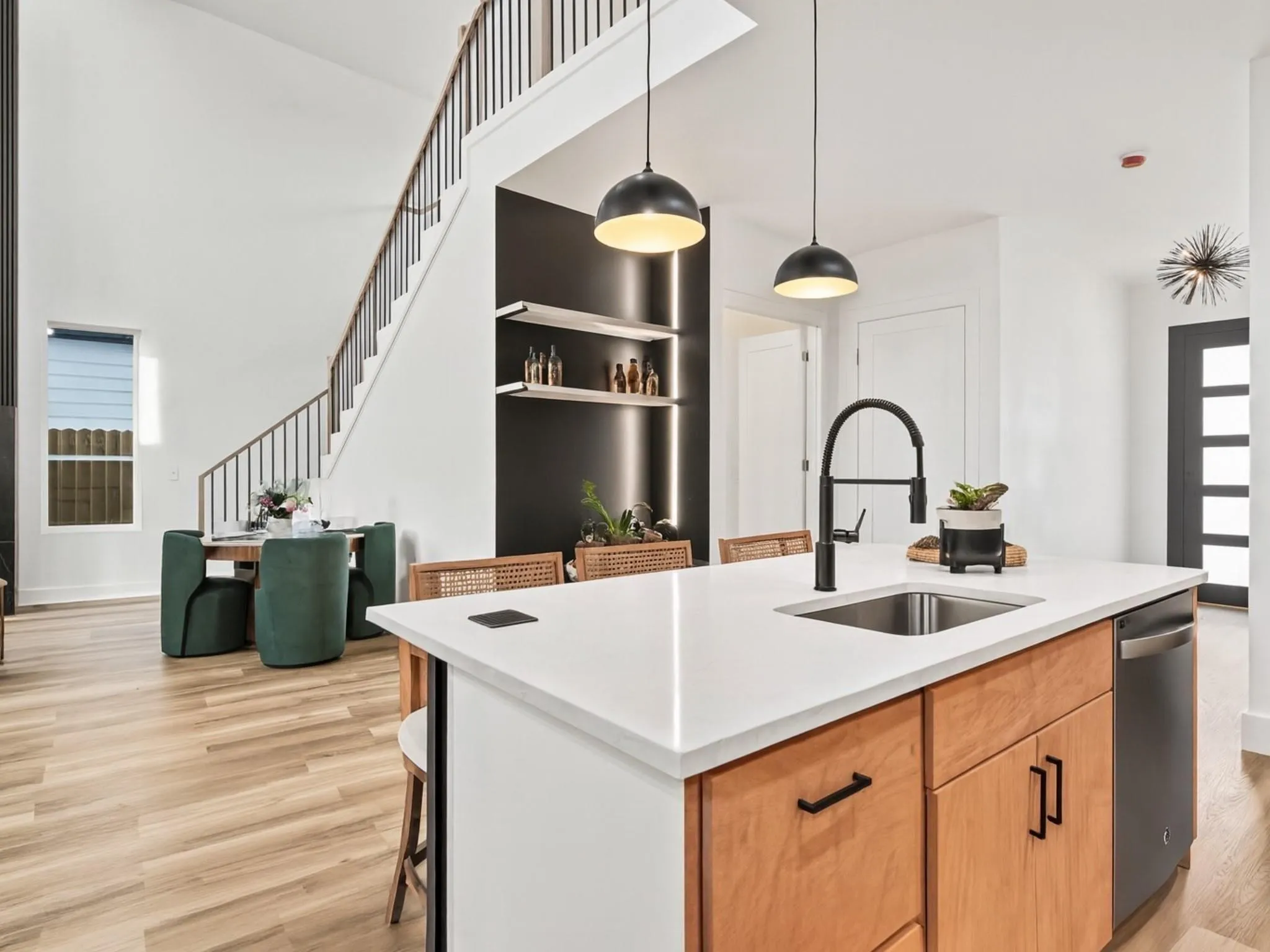 Kitchen island featuring a stainless steel sink, matte black faucet, integrated dishwasher, and wood-finish cabinetry
