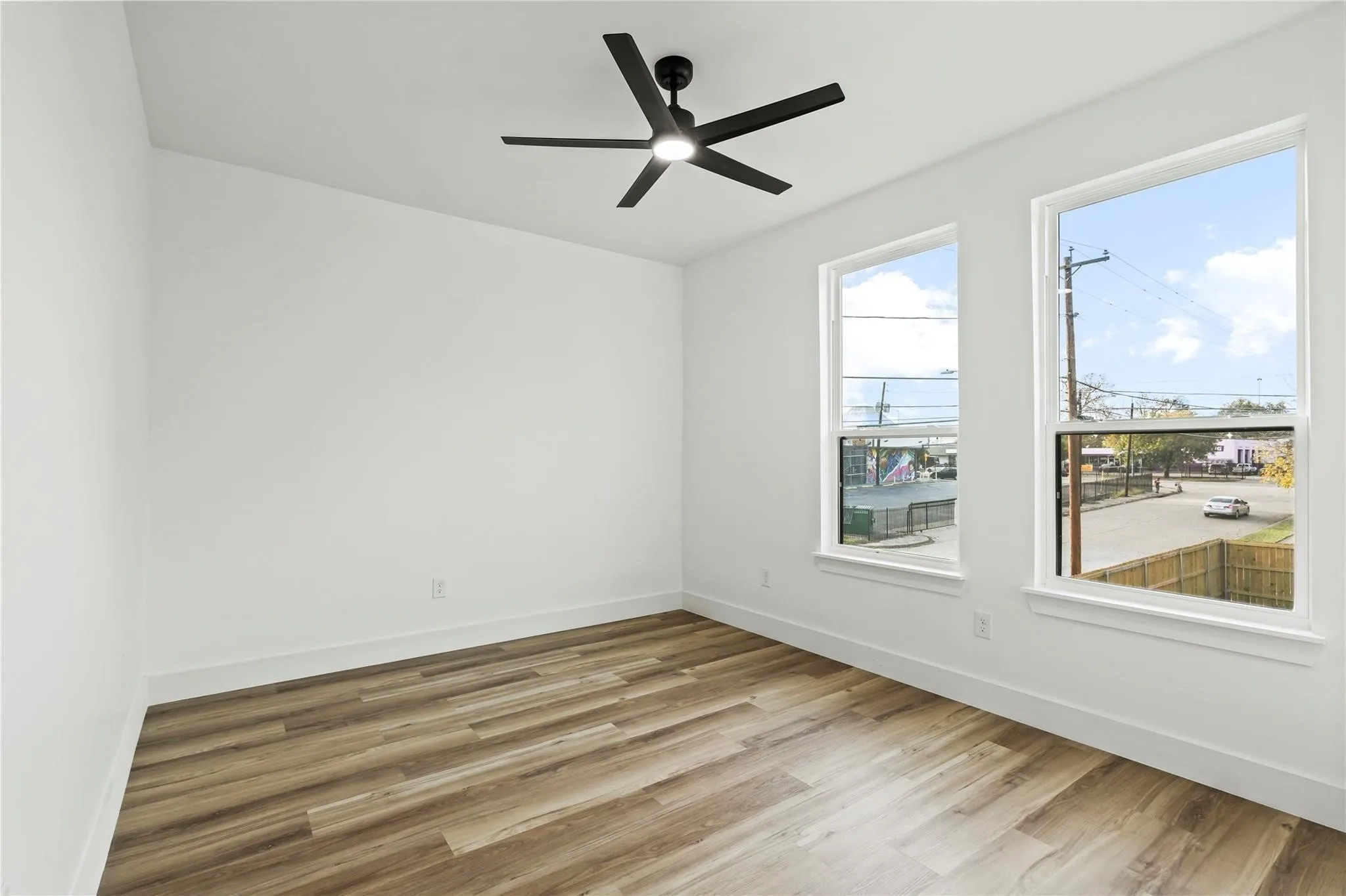 Bright interior space featuring wood-finish flooring, white walls, and a modern ceiling fan