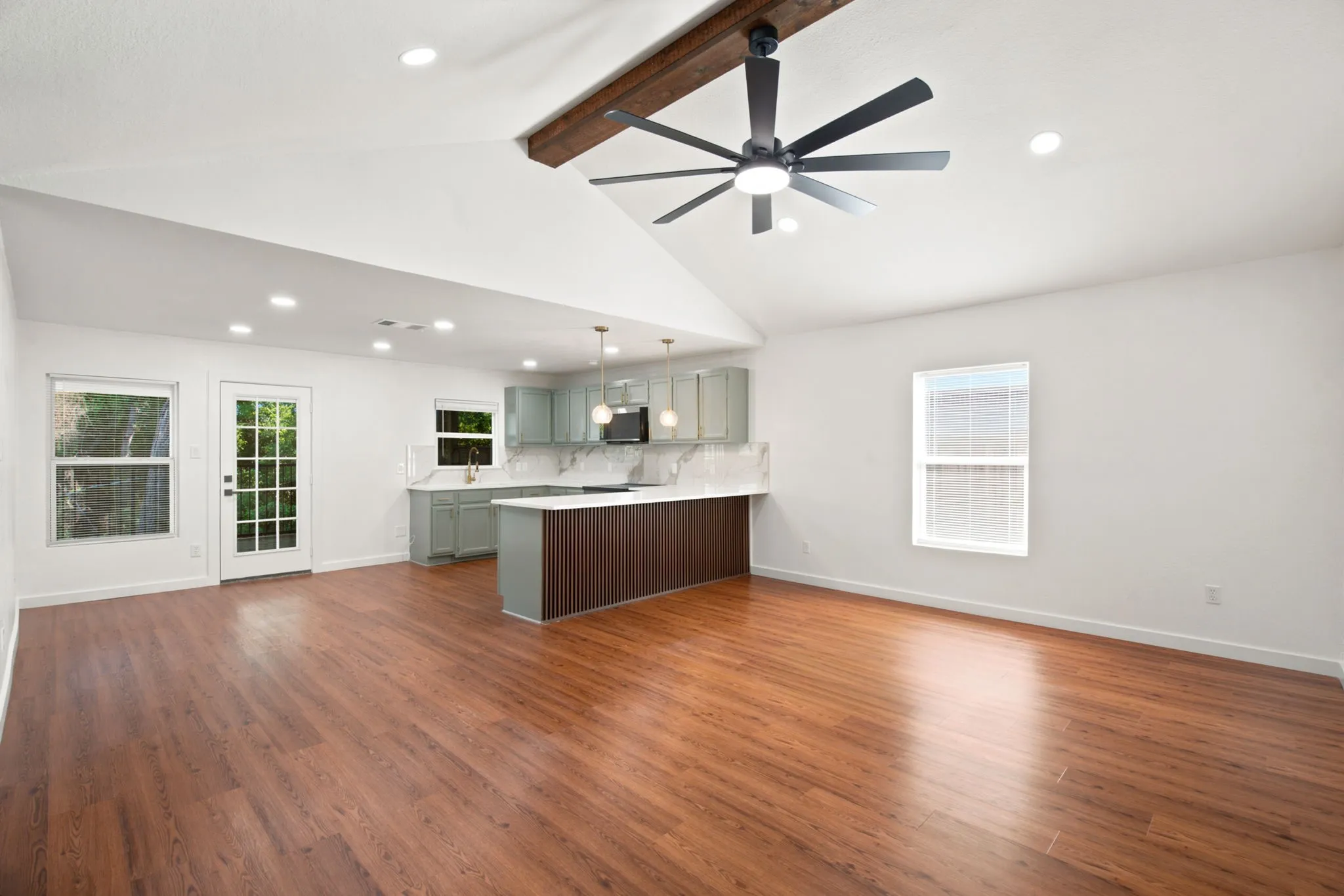 Open-concept living area with wood-finish flooring, vaulted ceilings, and recessed lighting