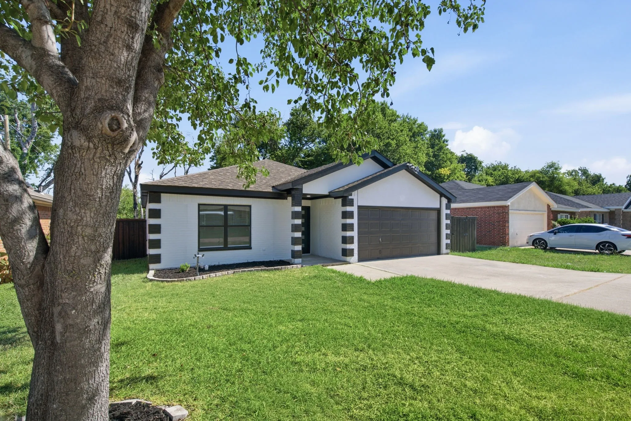 Contemporary exterior featuring a two-car garage, concrete driveway, and manicured front lawn