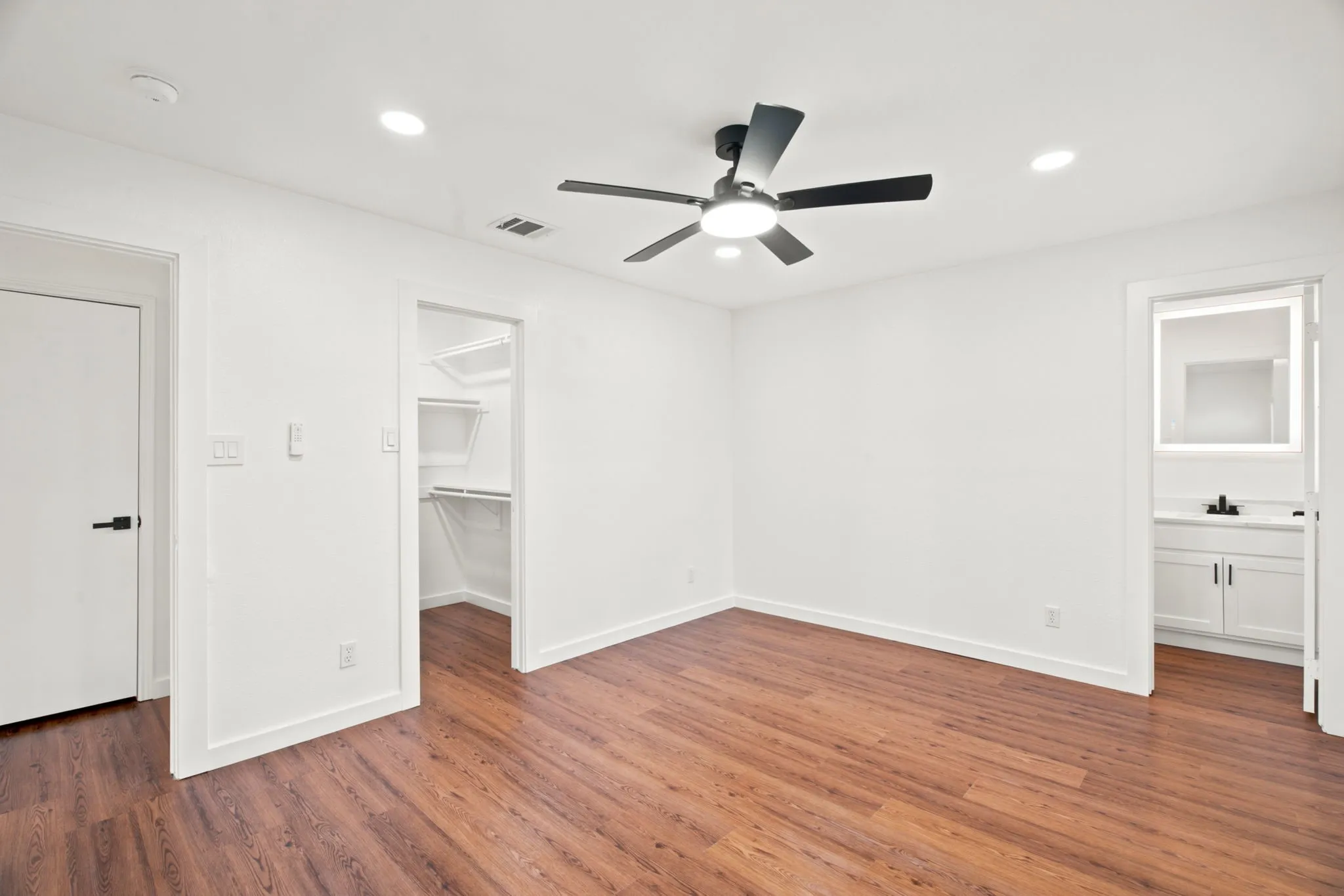 Spacious room featuring wood-finish flooring, recessed lighting, and a contemporary ceiling fan