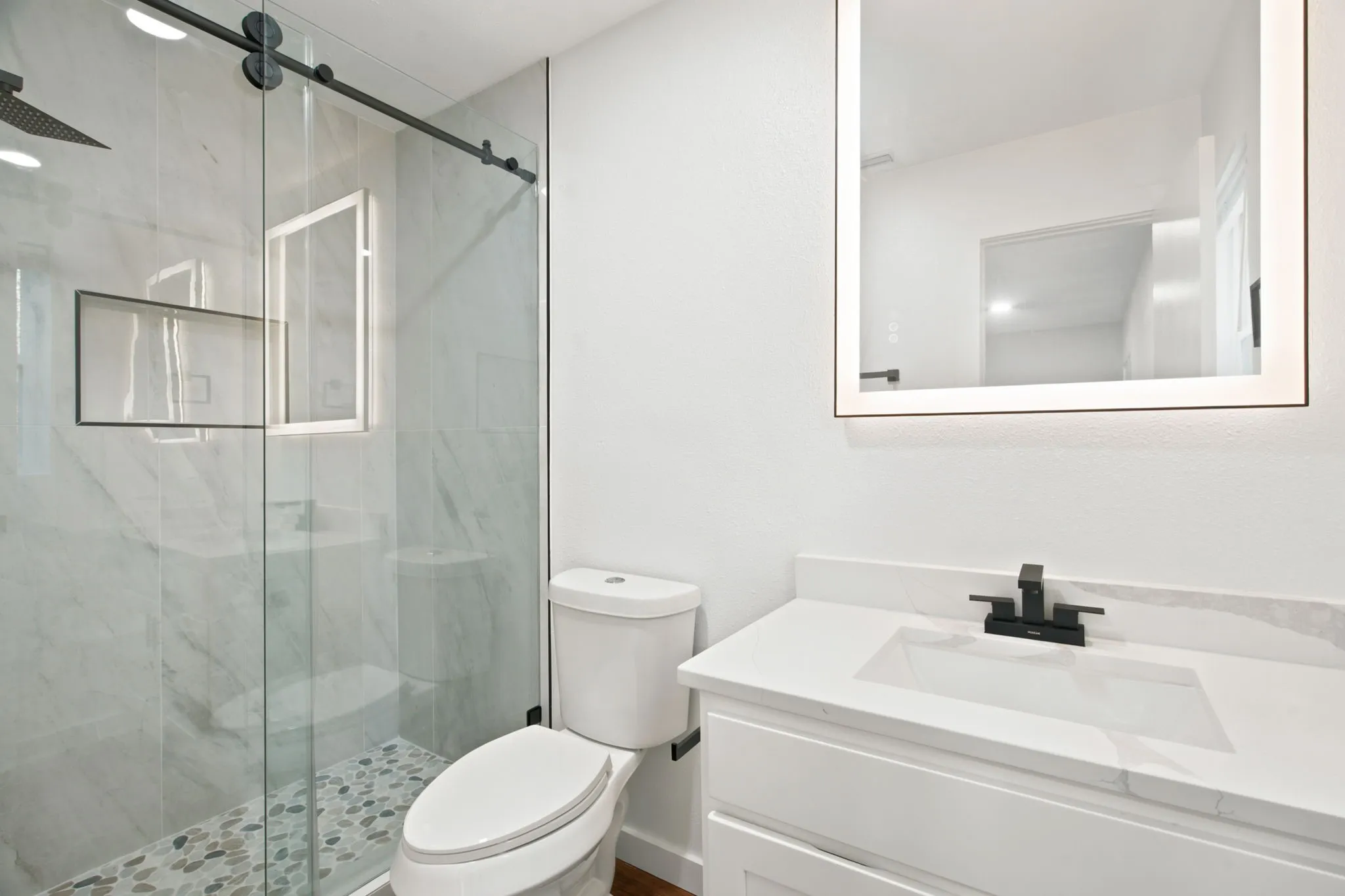 Bathroom featuring a glass-enclosed shower with pebble flooring and a built-in niche