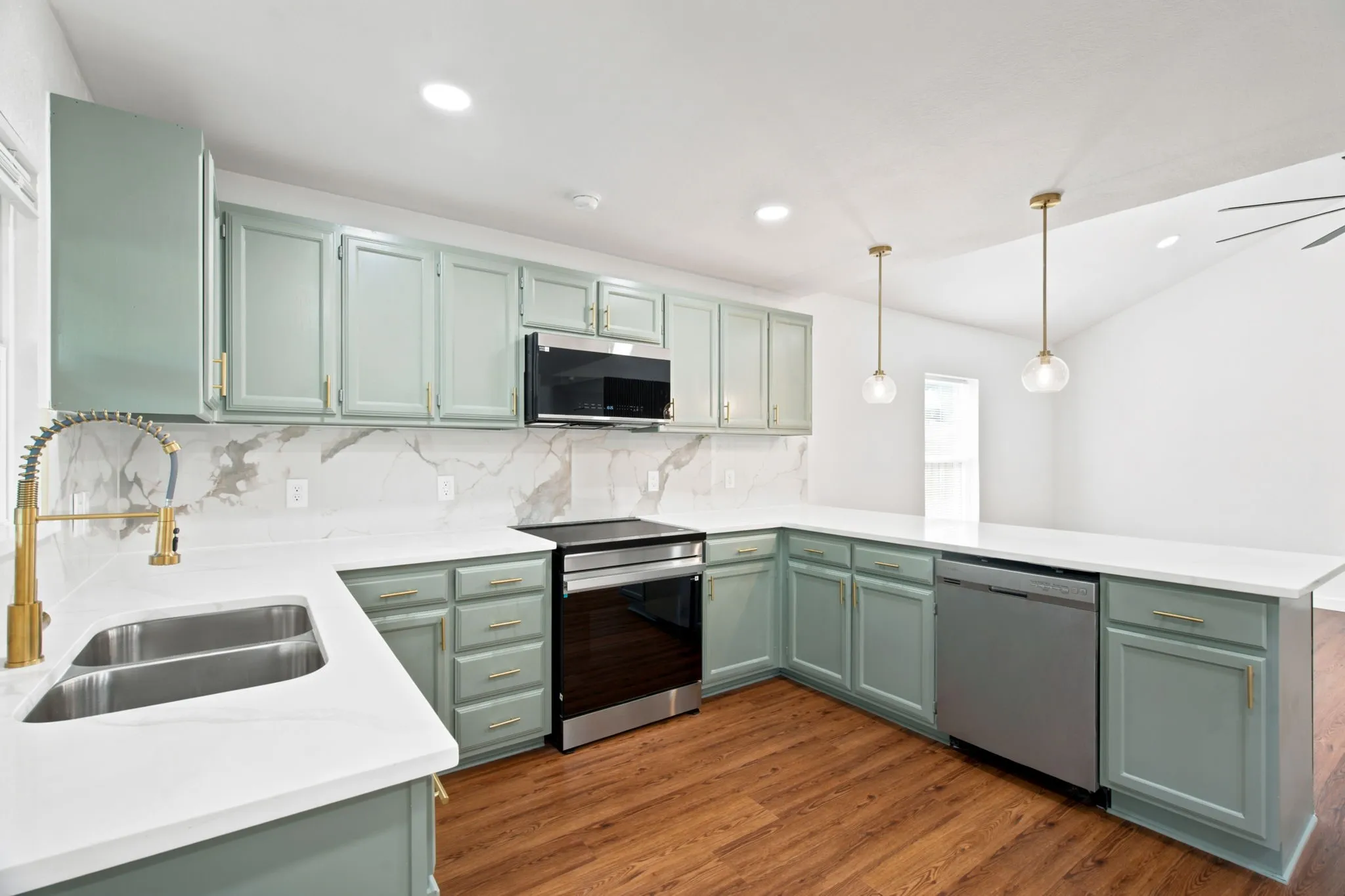 Kitchen featuring sage green cabinetry, white countertops, a stainless steel sink with gold-tone faucet, and an integrated stainless steel dishwasher