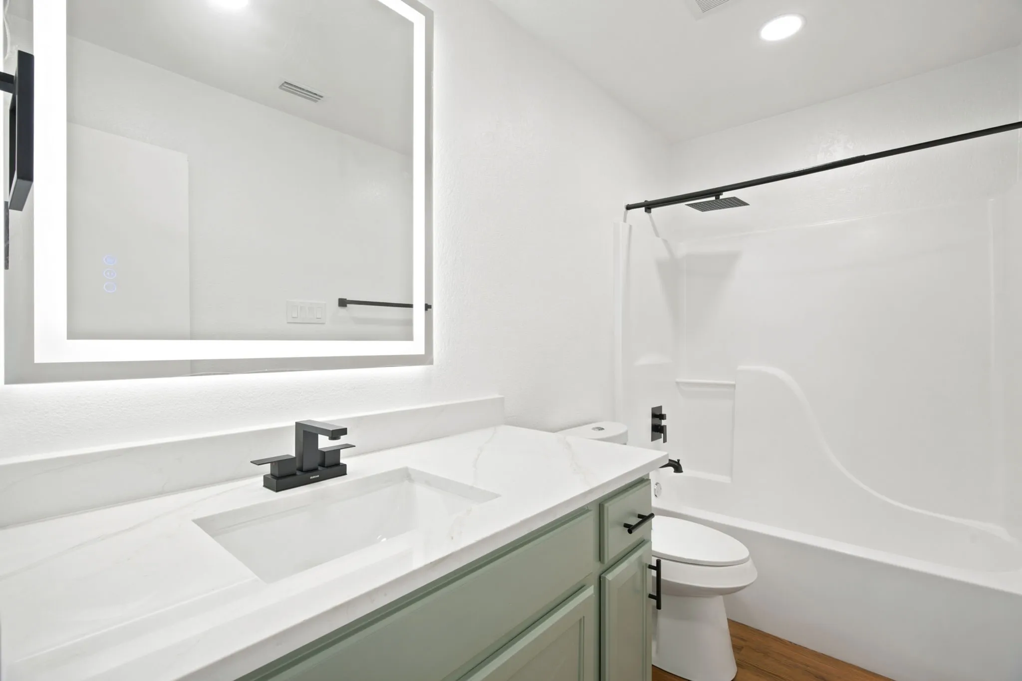 Bathroom featuring a vanity with a white countertop and rectangular undermount sink, illuminated mirror, and matte black fixtures