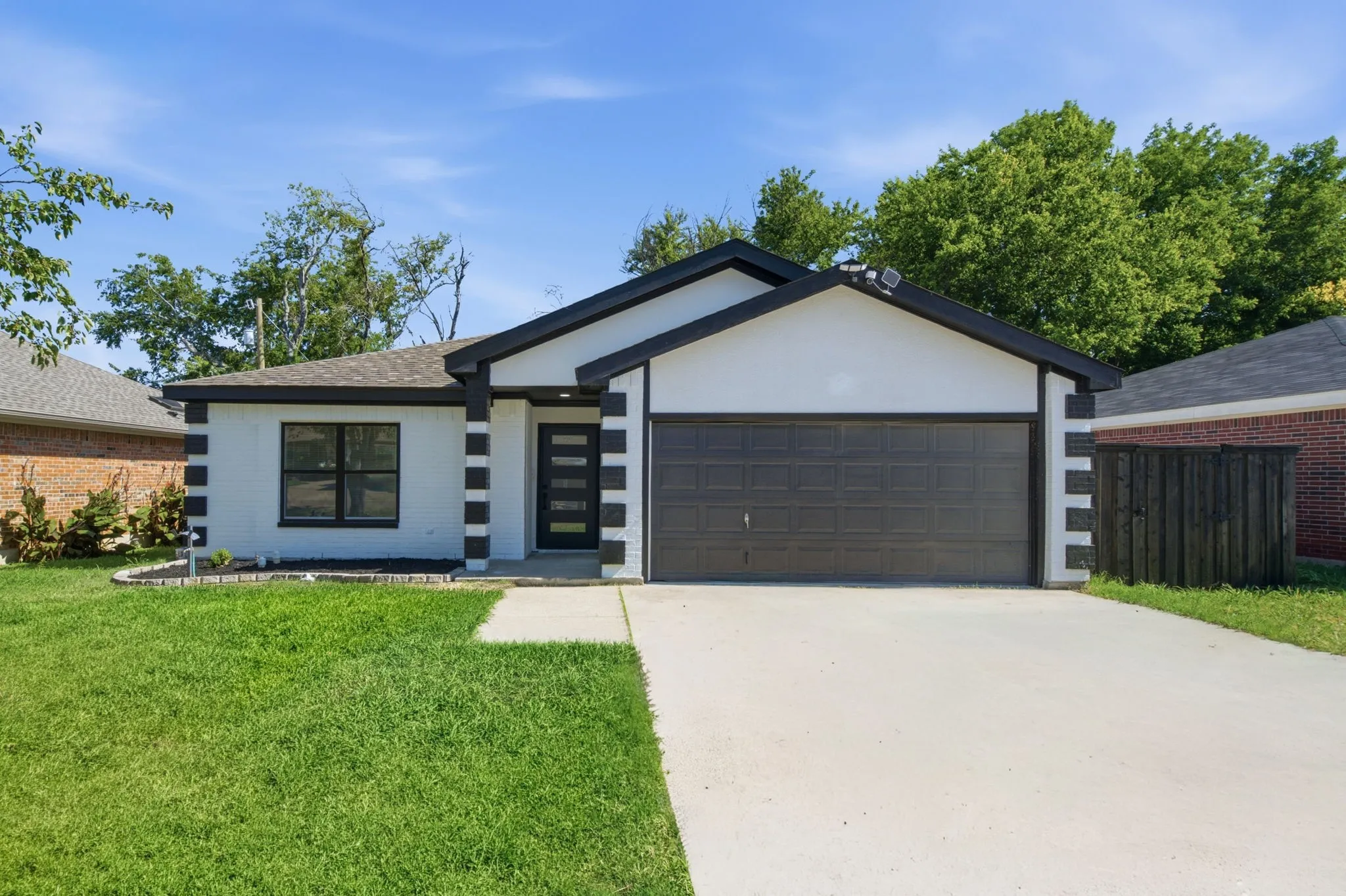Contemporary exterior featuring white brick with black trim accents and a dark-toned garage door