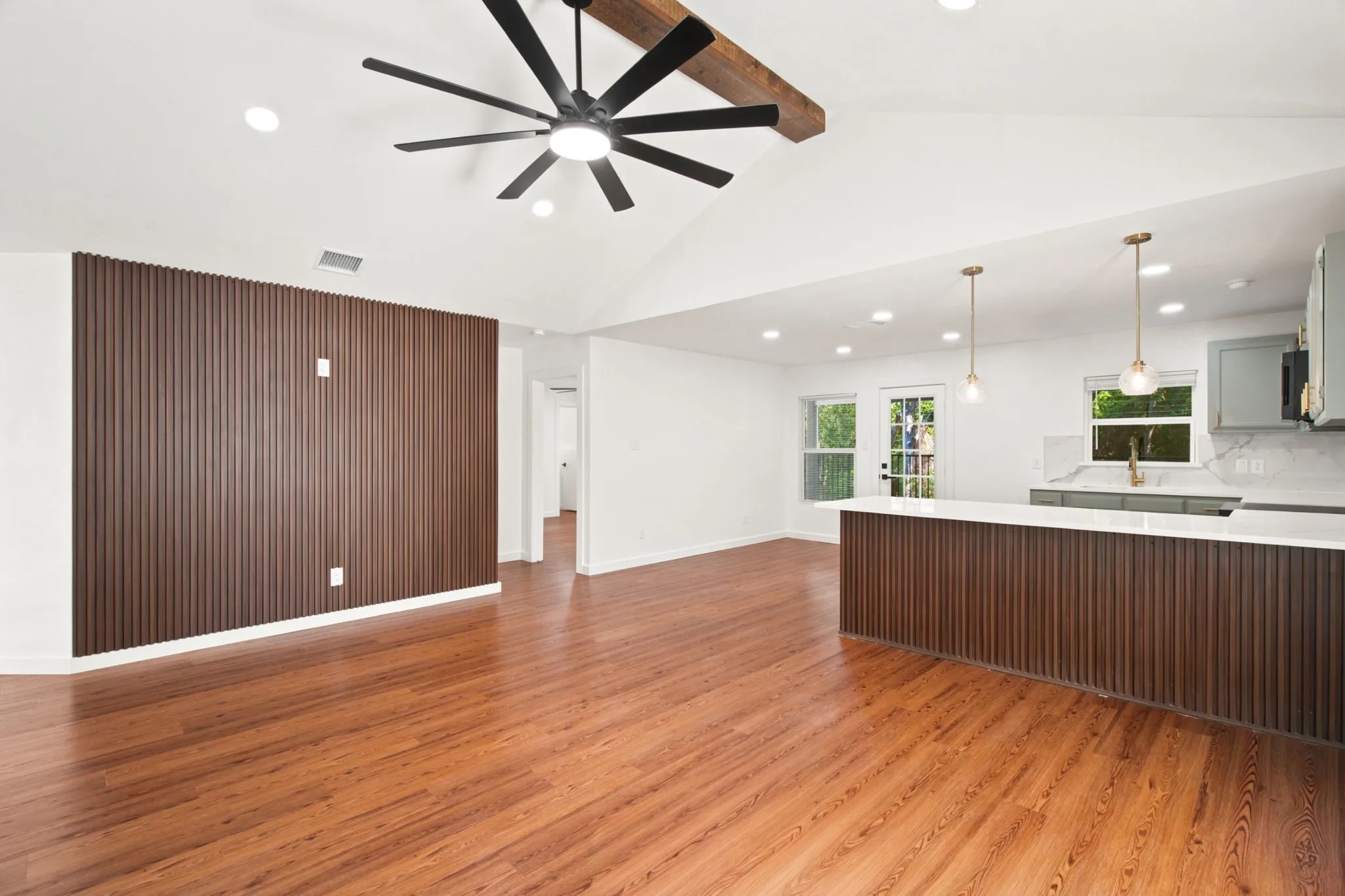 Open-concept living space featuring wood-finish flooring and a vaulted ceiling with a prominent wood beam