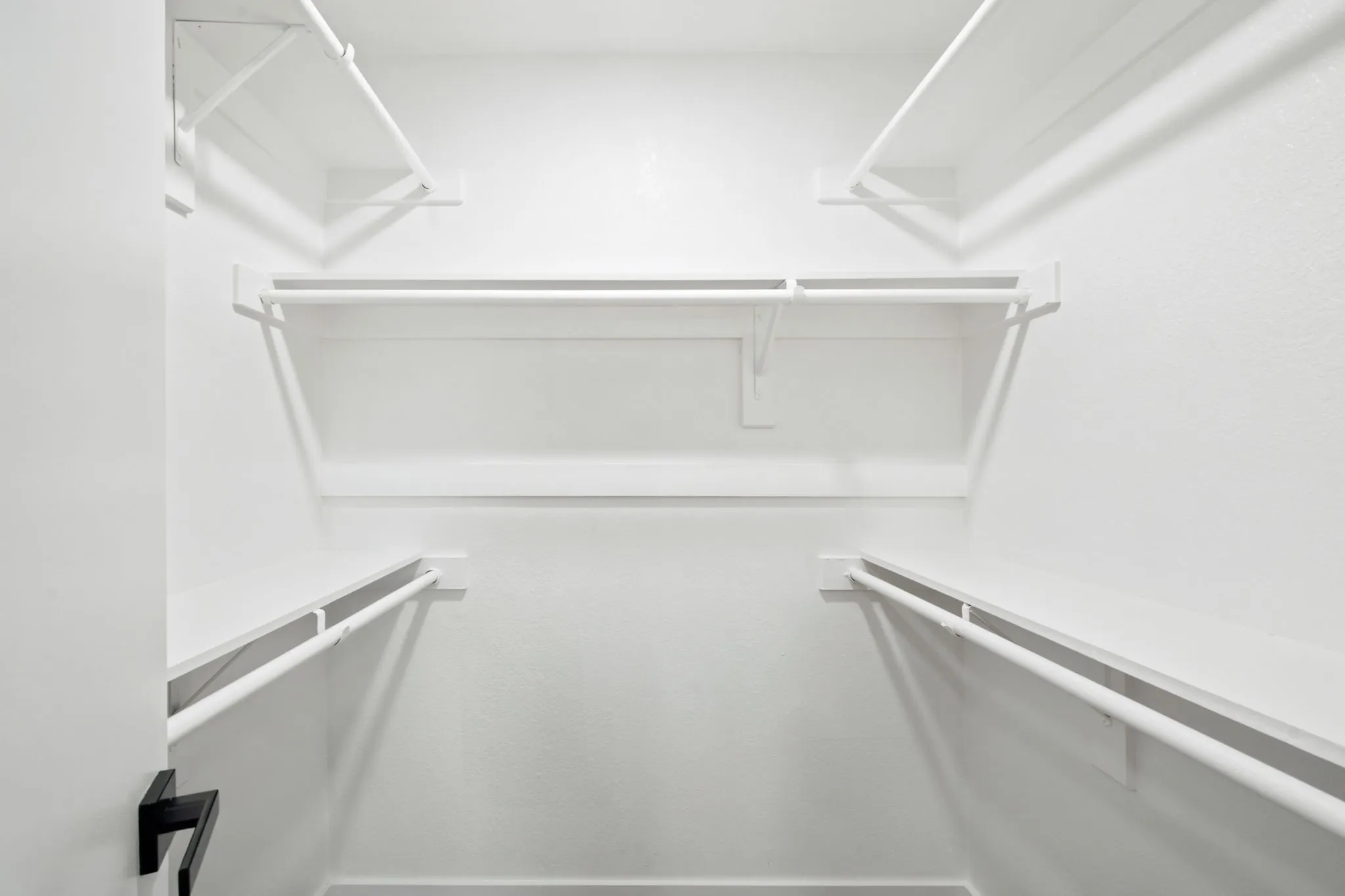 Walk-in closet featuring white wire shelving and hanging rods