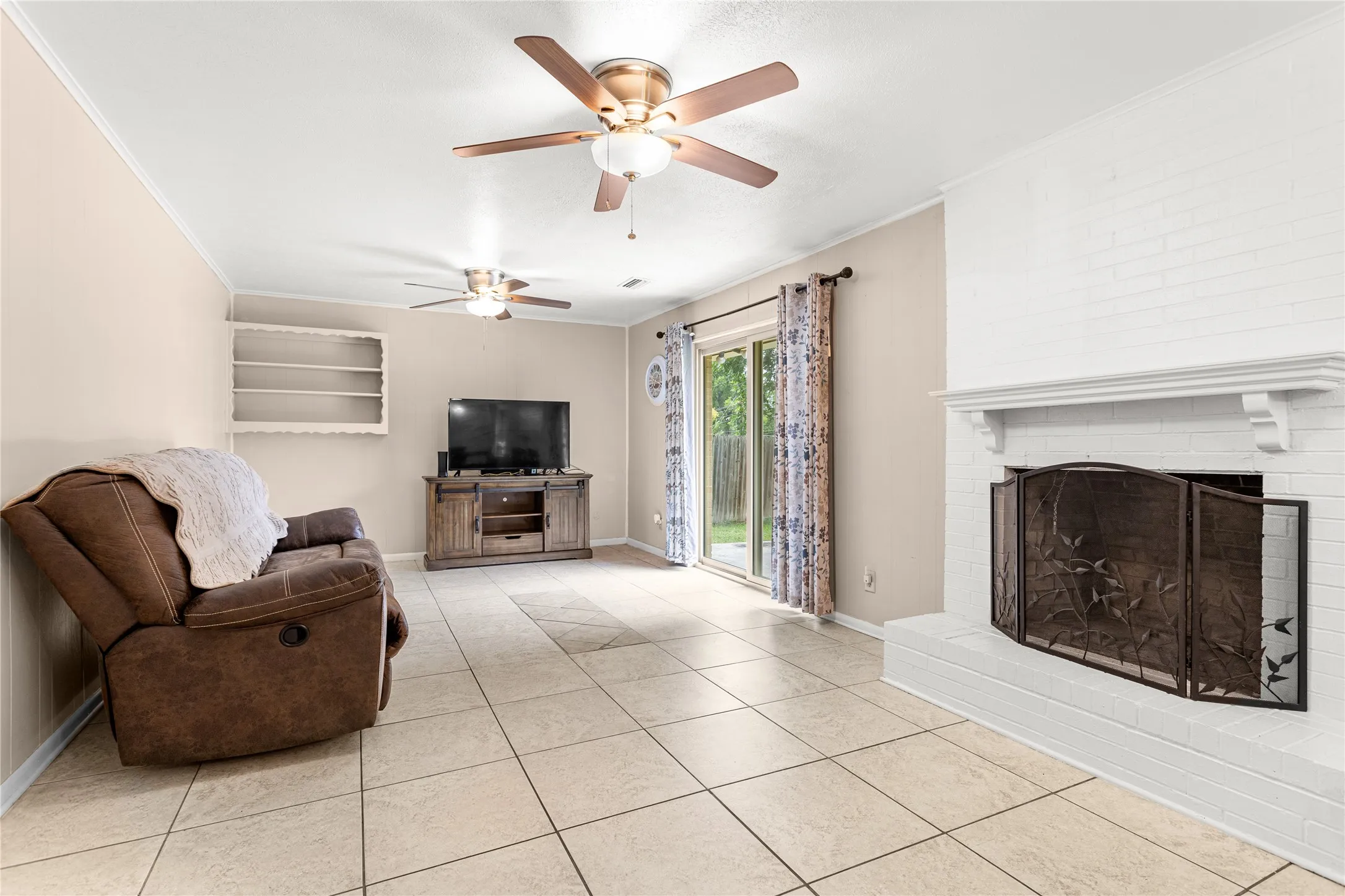 Living room with light-toned square tile flooring, a white-painted brick fireplace with a decorative screen, and a white mantelpiece