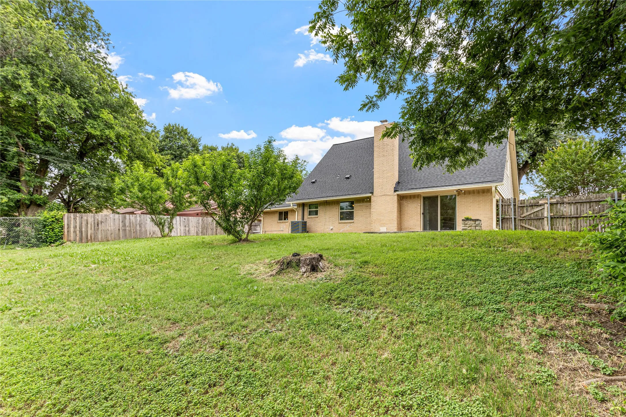 Spacious backyard with a gentle slope and mature trees