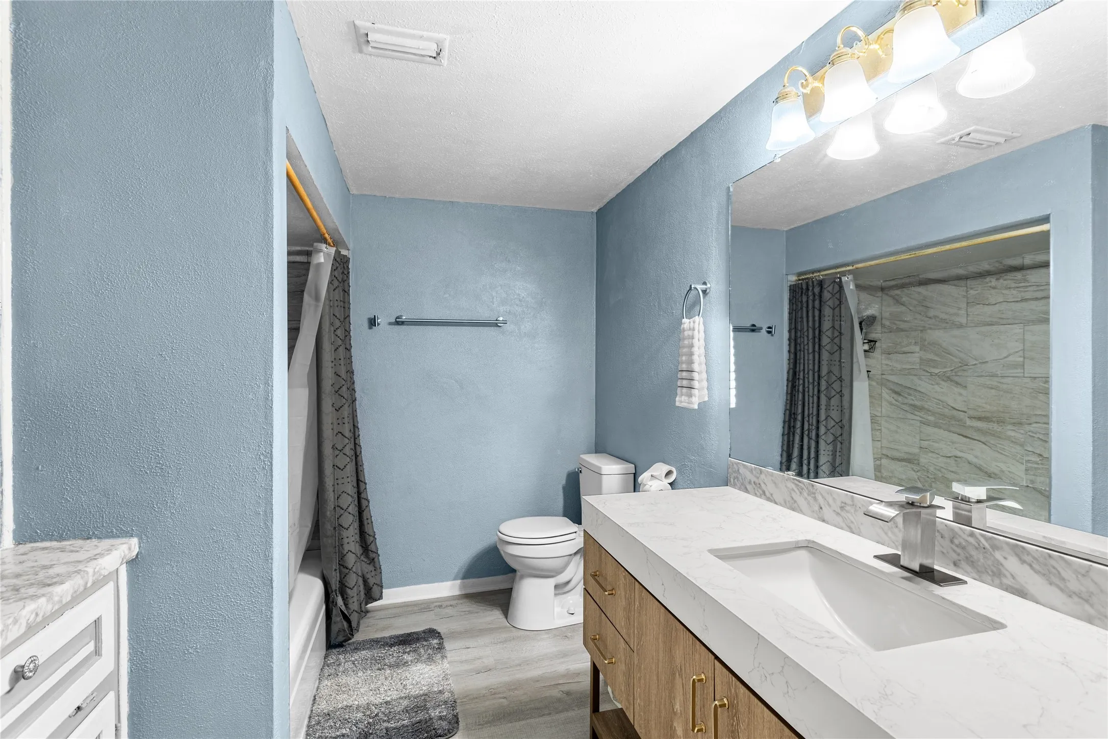Bathroom featuring a single vanity with an integrated sink, a large mirror, and a shower-tub combination