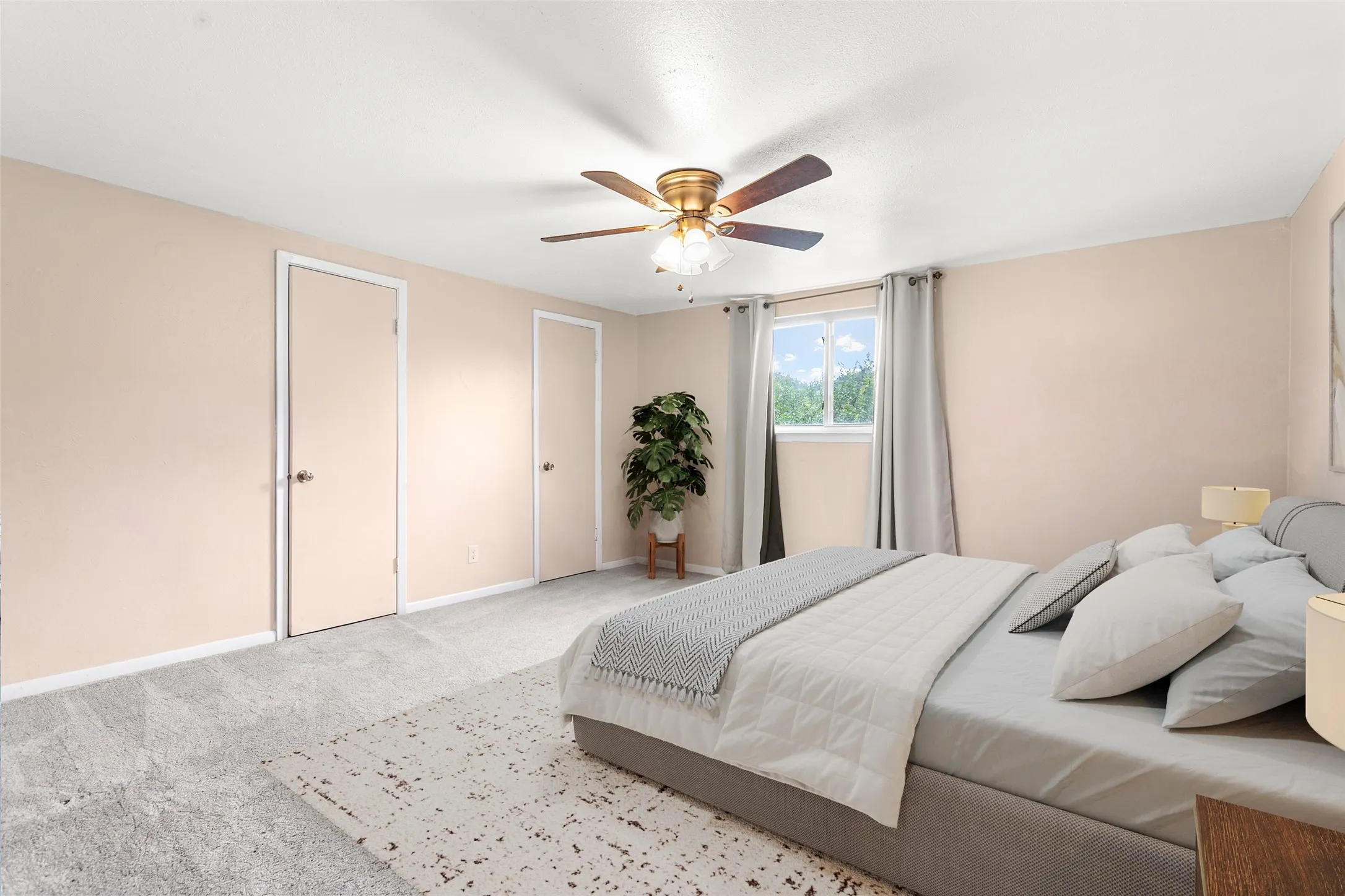 Virtually Staged Spacious room featuring light-toned walls, plush grey carpeting, a window with exterior visibility, and a ceiling fan with integrated lighting