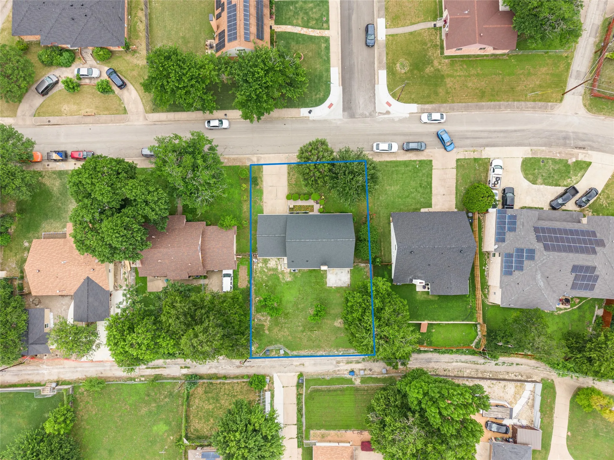 Aerial perspective showcasing a residential property with a dark shingle roof and a concrete driveway