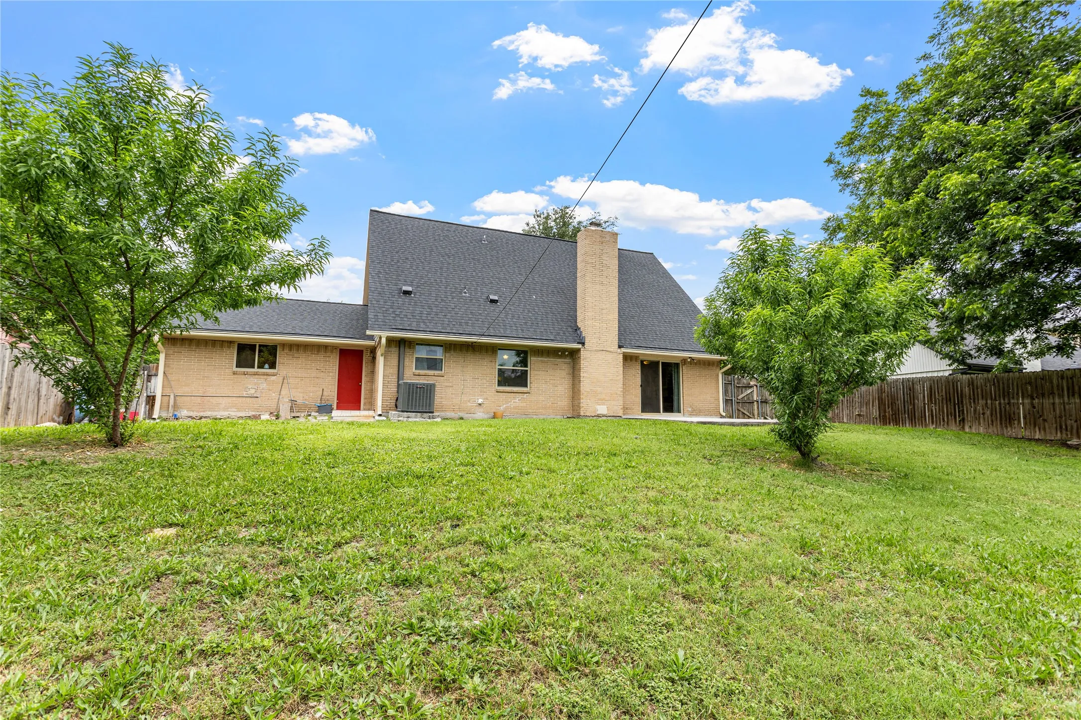 Expansive backyard featuring a lush lawn, mature trees, and a privacy fence