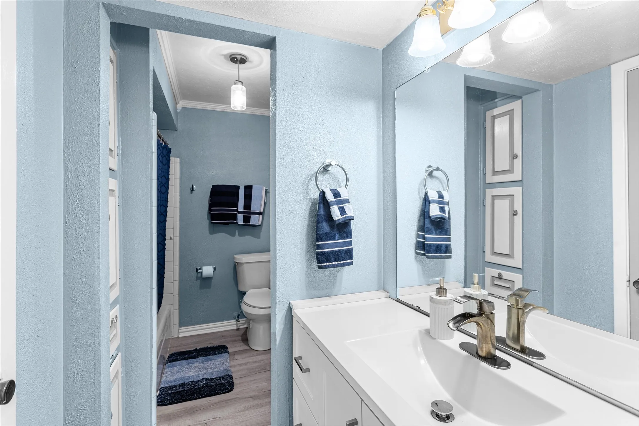 Bathroom vanity with a large mirror, integrated sink, and brushed nickel fixtures