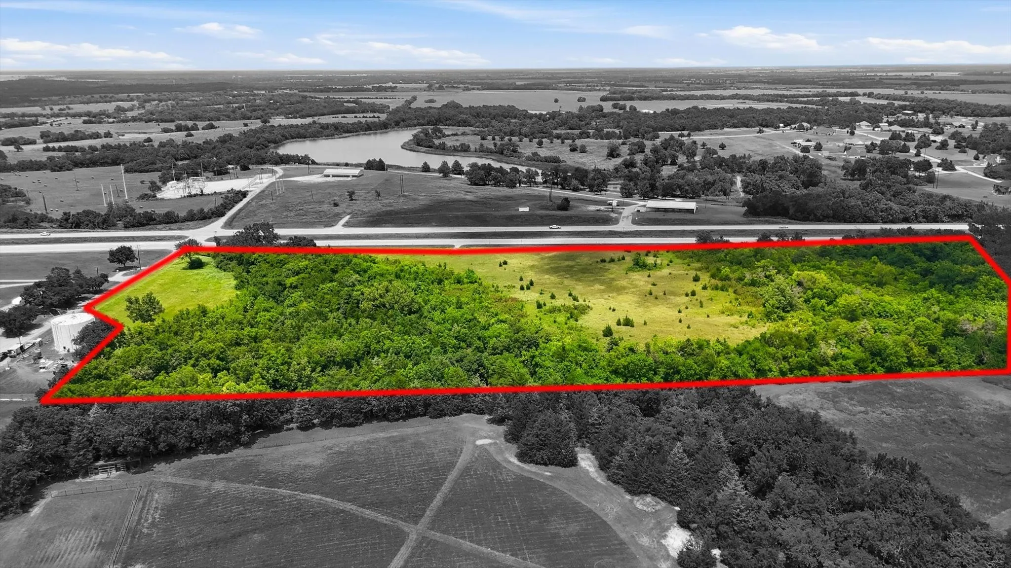 Expansive land parcel with significant tree coverage and clearings, bordered by a main road