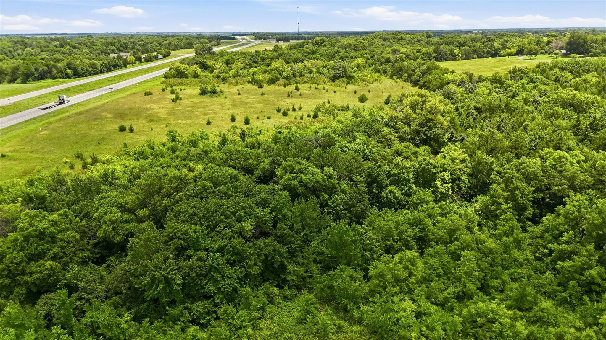 Expansive natural landscape featuring lush green foliage and open grassy areas