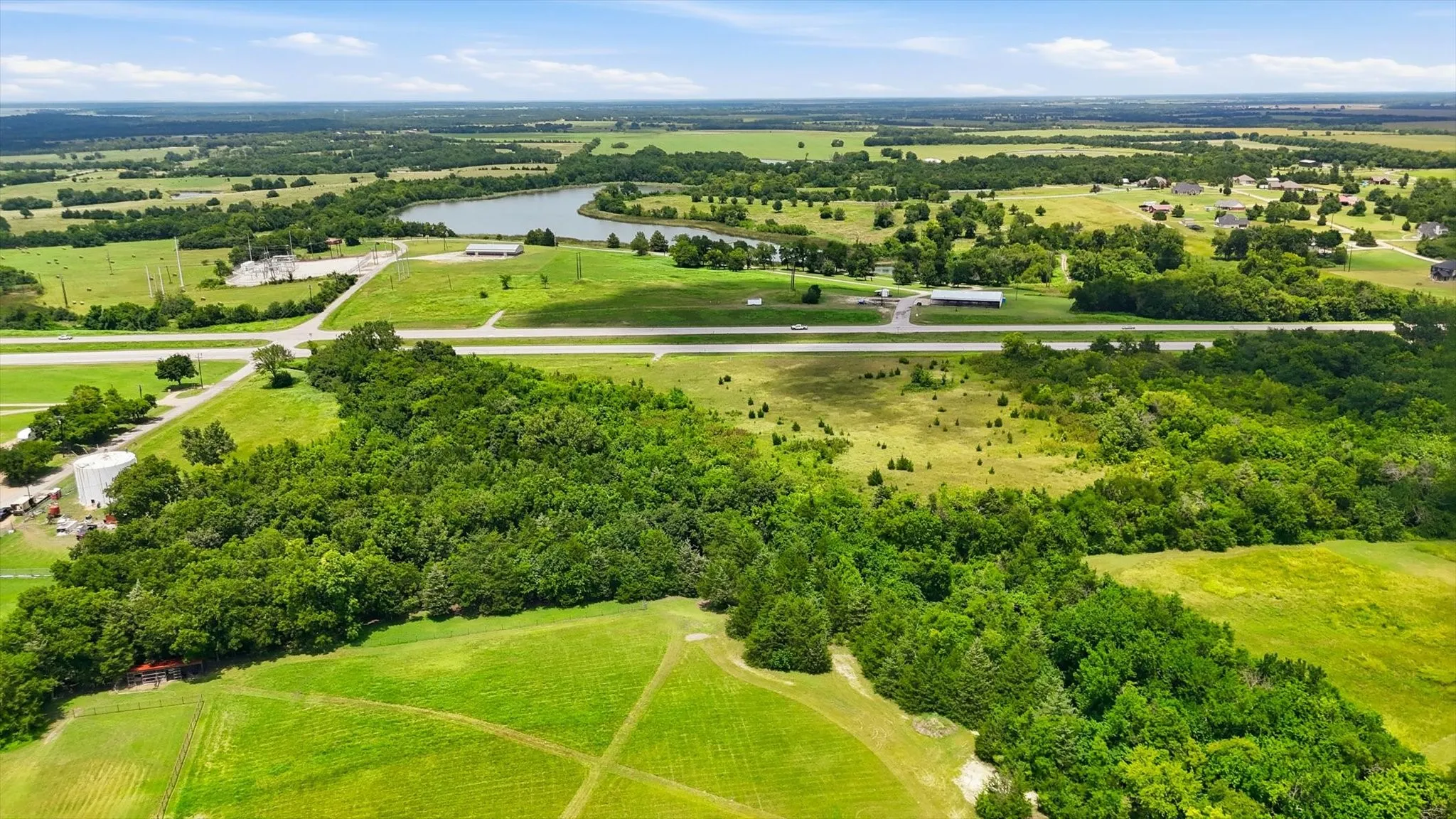 Expansive land parcel featuring diverse topography, mature tree lines, open green spaces, and a prominent roadway