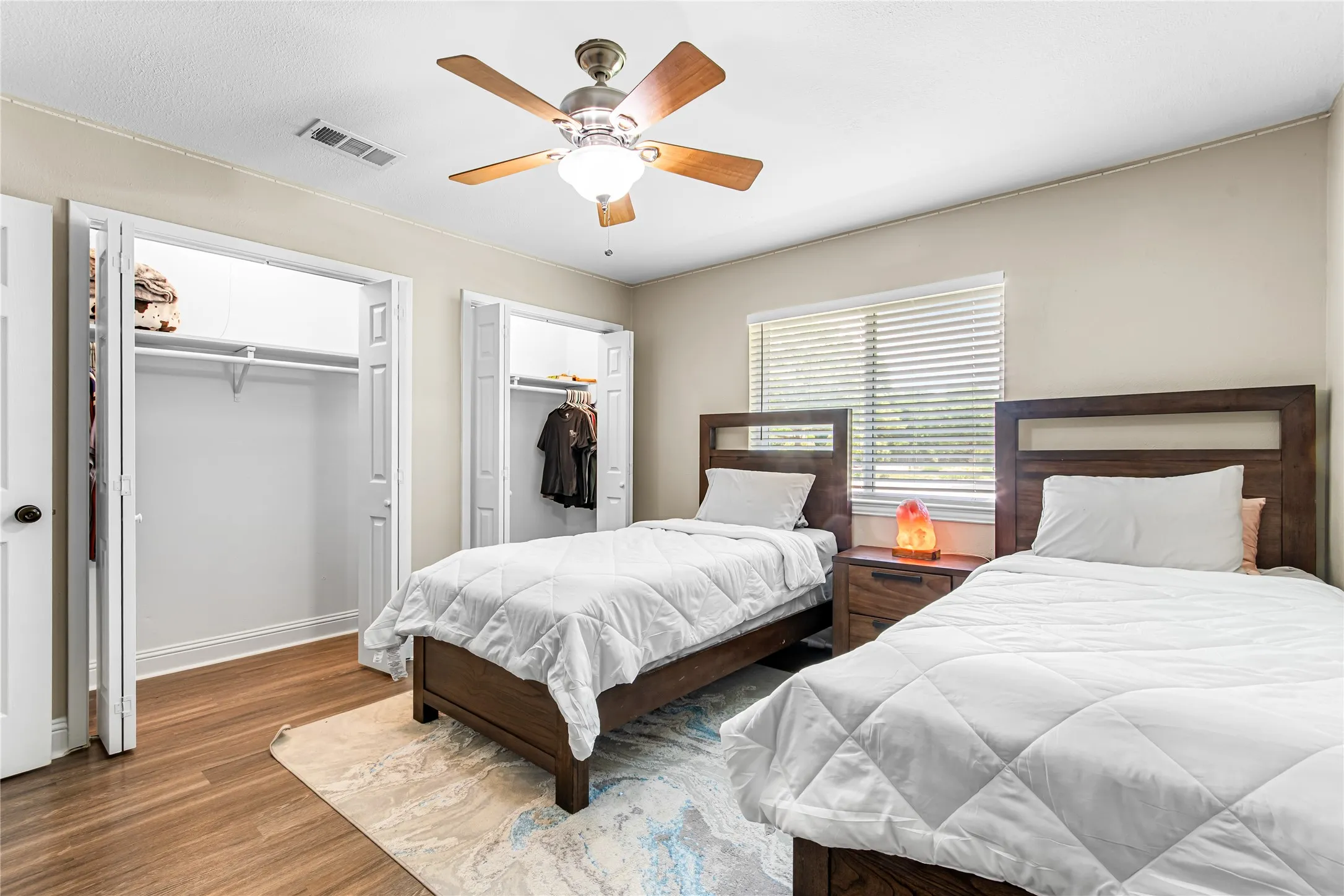 Bedroom featuring woodlike-finish flooring, neutral wall tones, and a ceiling fan with integrated lighting