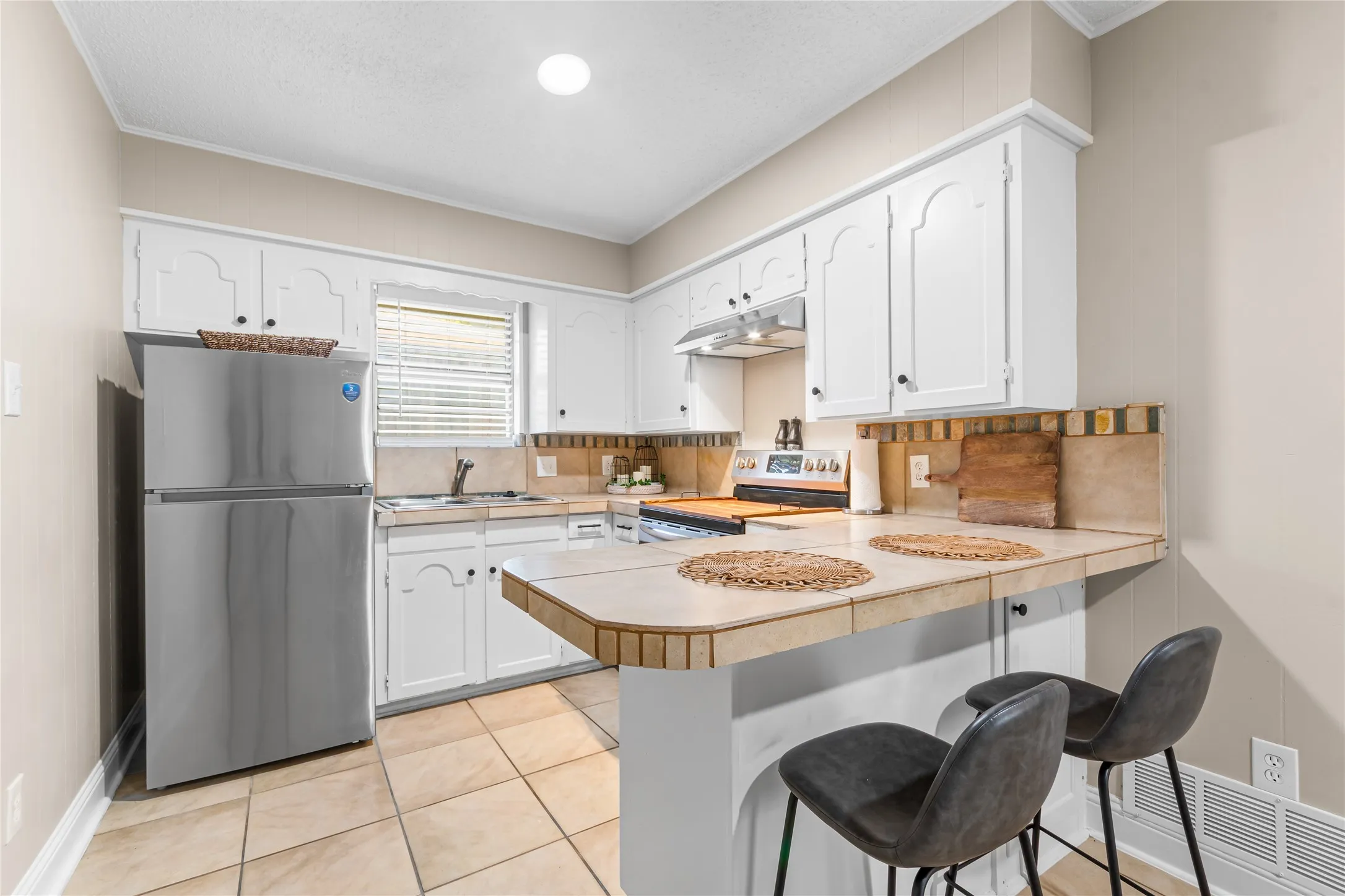 Casita Kitchen featuring white cabinetry, tile countertops, tile backsplash, and tile flooring